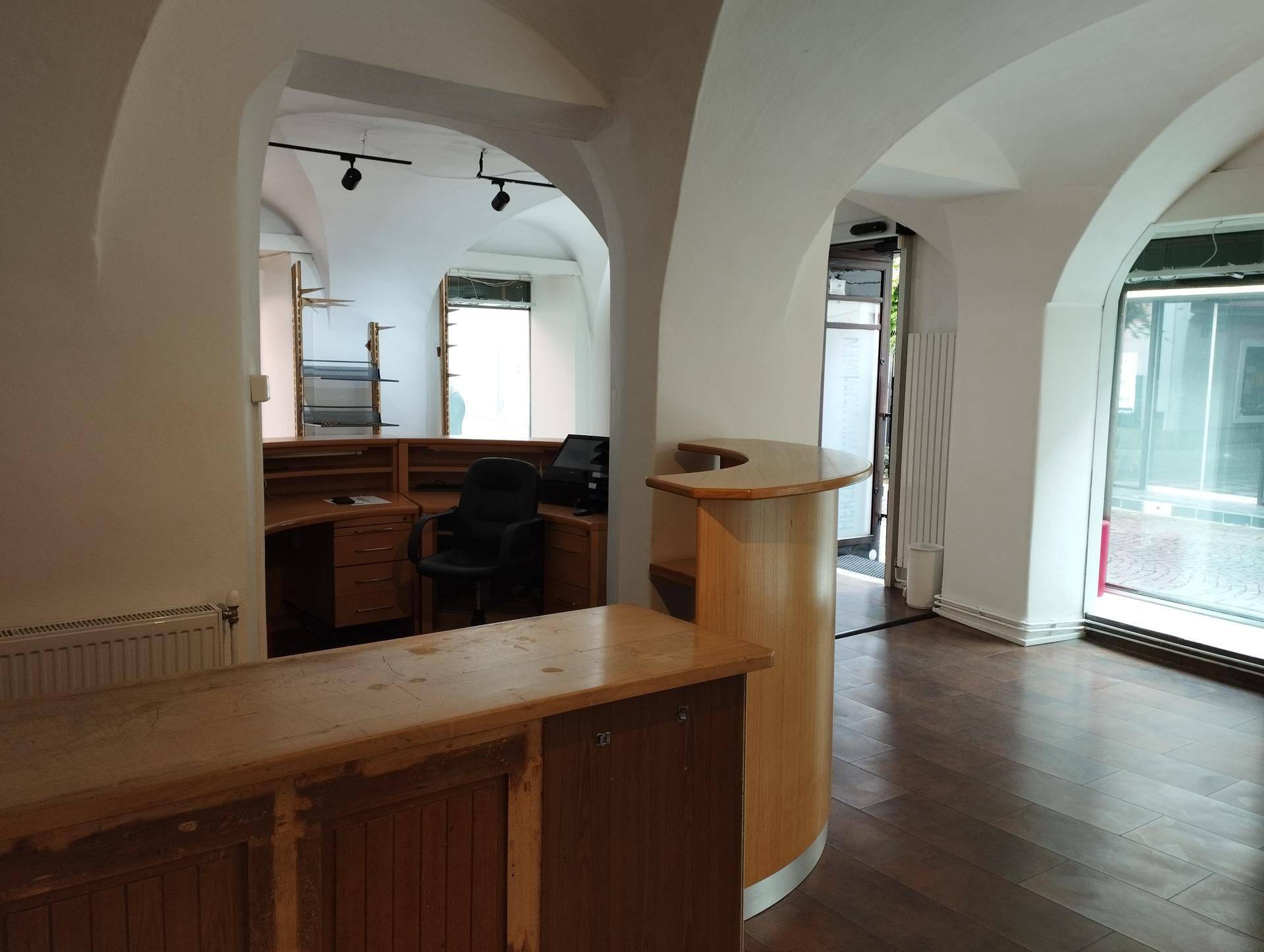 Gewerbefläche mit gewölbten Decken, Holzboden und einer Holzrezeption, die viel Tageslicht durch große Fenster erhält.