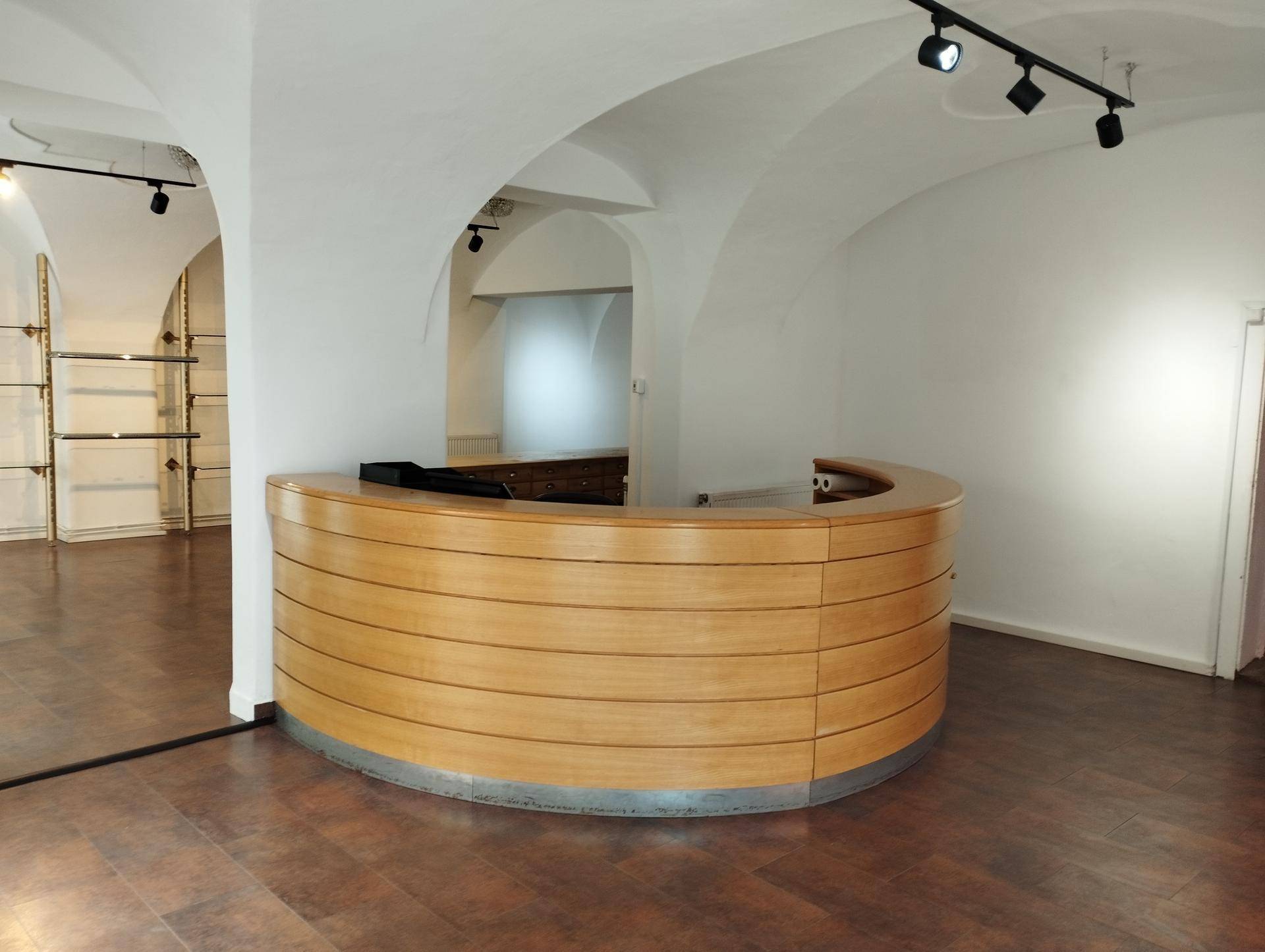 Geräumige Gewerbefläche mit einer großen, geschwungenen Holzrezeption, dunklem Holzboden und gewölbten Decken.