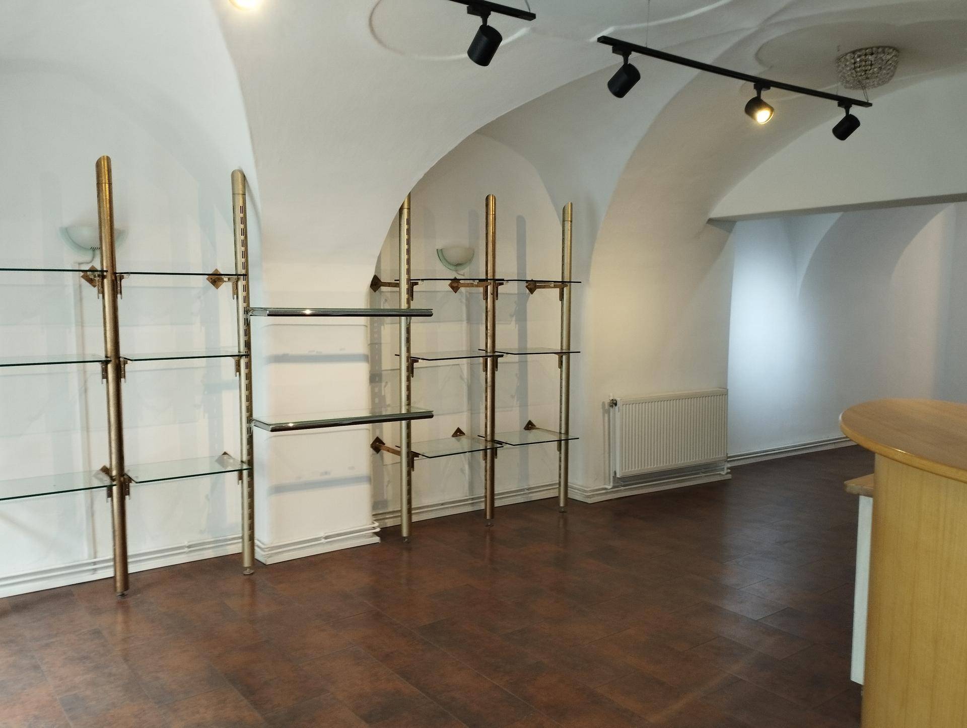 Gewerbefläche mit gewölbten Decken, dunklem Holzboden und eleganten Glasregalen für die Warenpräsentation.