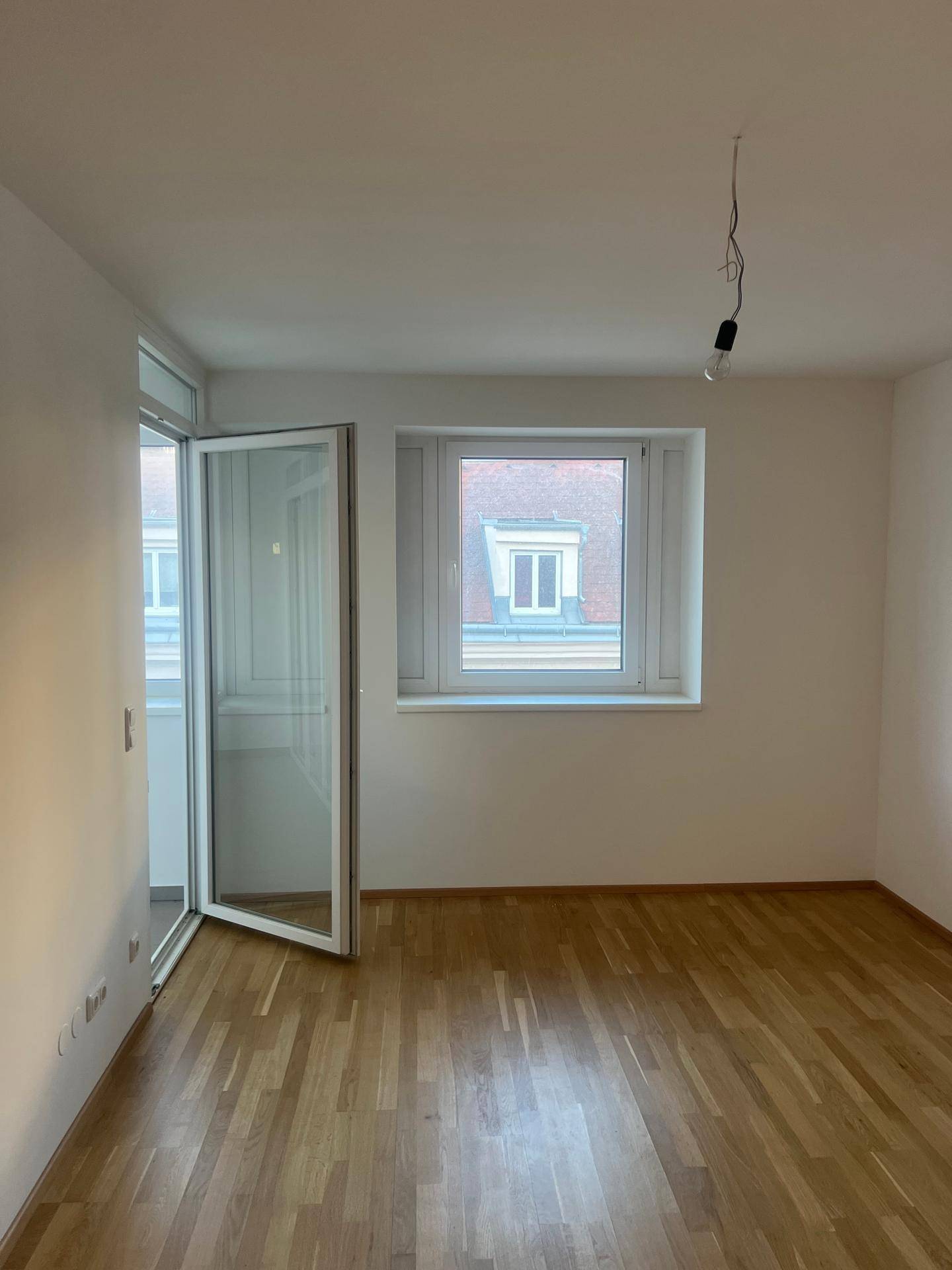 Helles Zimmer mit Holzboden und Fenster, das viel Tageslicht in den Raum bringt.