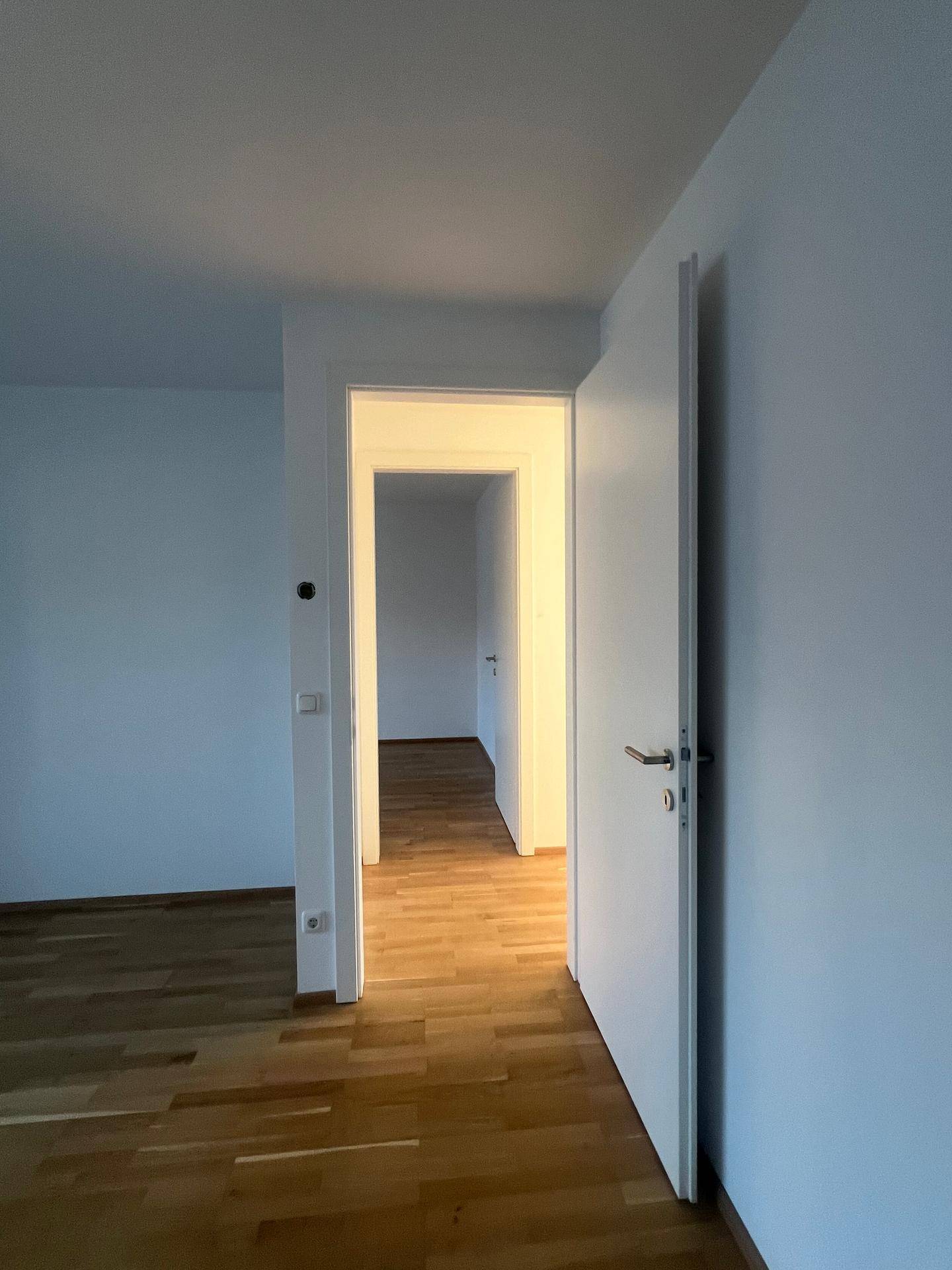 Heller Flur mit Holzboden, der zu weiteren Zimmern der Wohnung führt.
