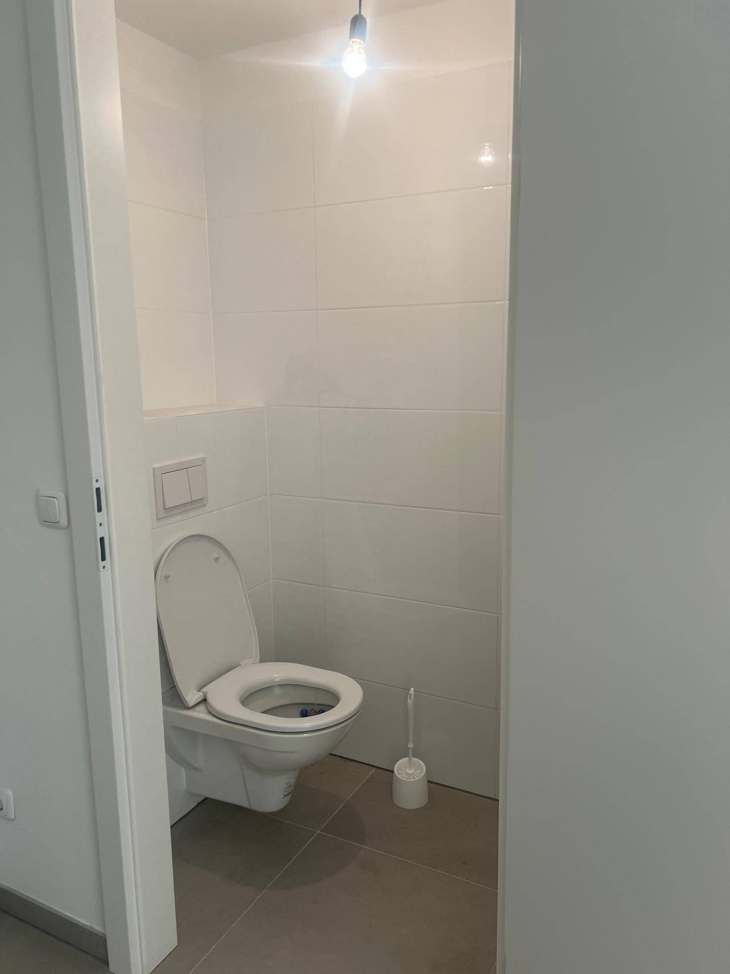 Modernes Gäste-WC mit Wand-WC und weißen Fliesen, in neuwertigem Zustand.