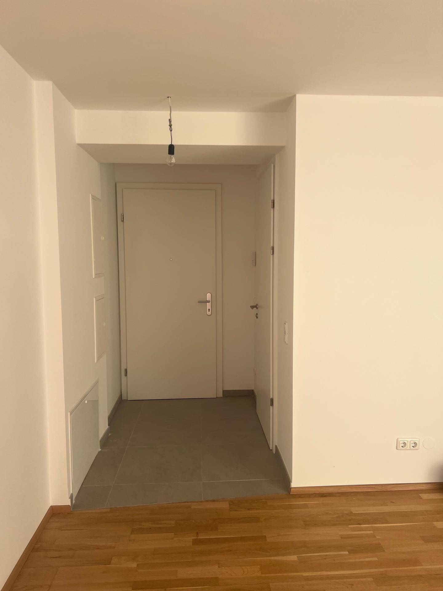 Eingangsbereich mit Fliesenboden und weißer Tür, die zu den Wohnräumen führt.