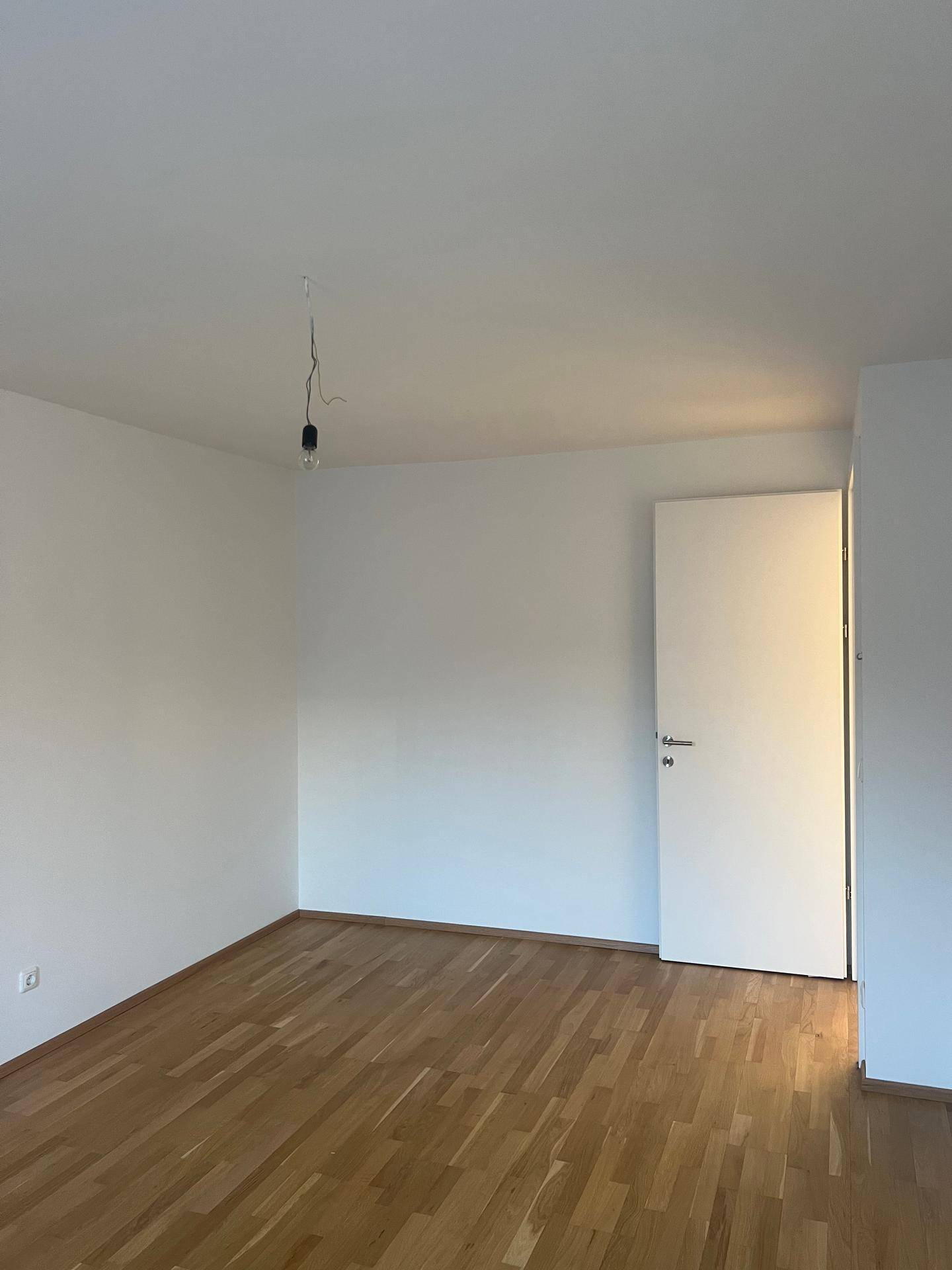 Ruhiges Schlafzimmer mit Holzboden und weiß gestrichenen Wänden, bereit zum Einzug.