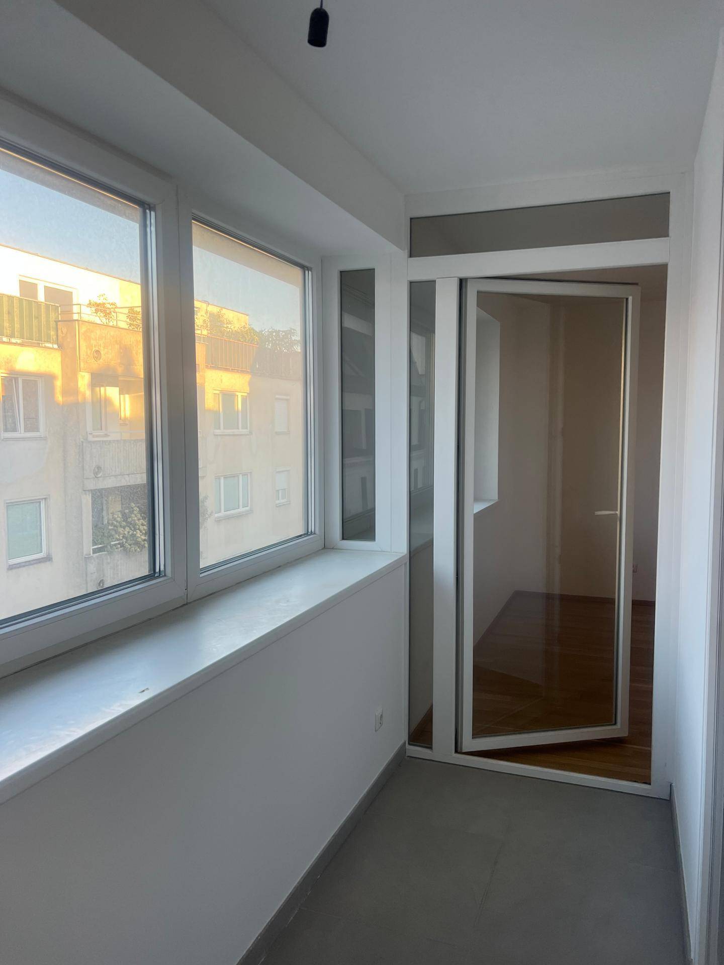 Verglaster Balkon mit Fliesenboden und weitem Blick auf die umliegenden Gebäude.