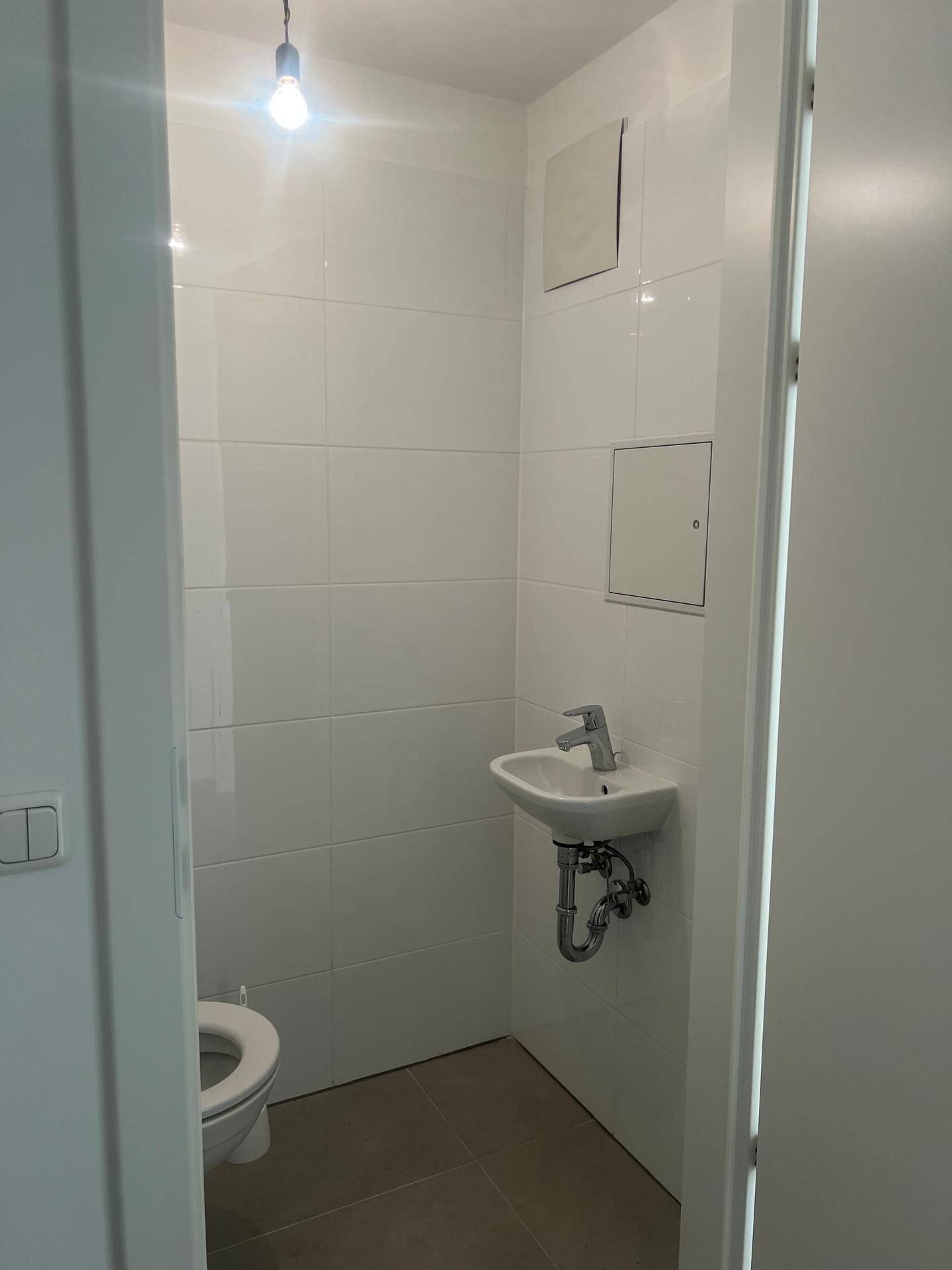 Helles Gäste-WC mit kleinem Waschbecken und weißen Fliesen, ideal für Besucher.
