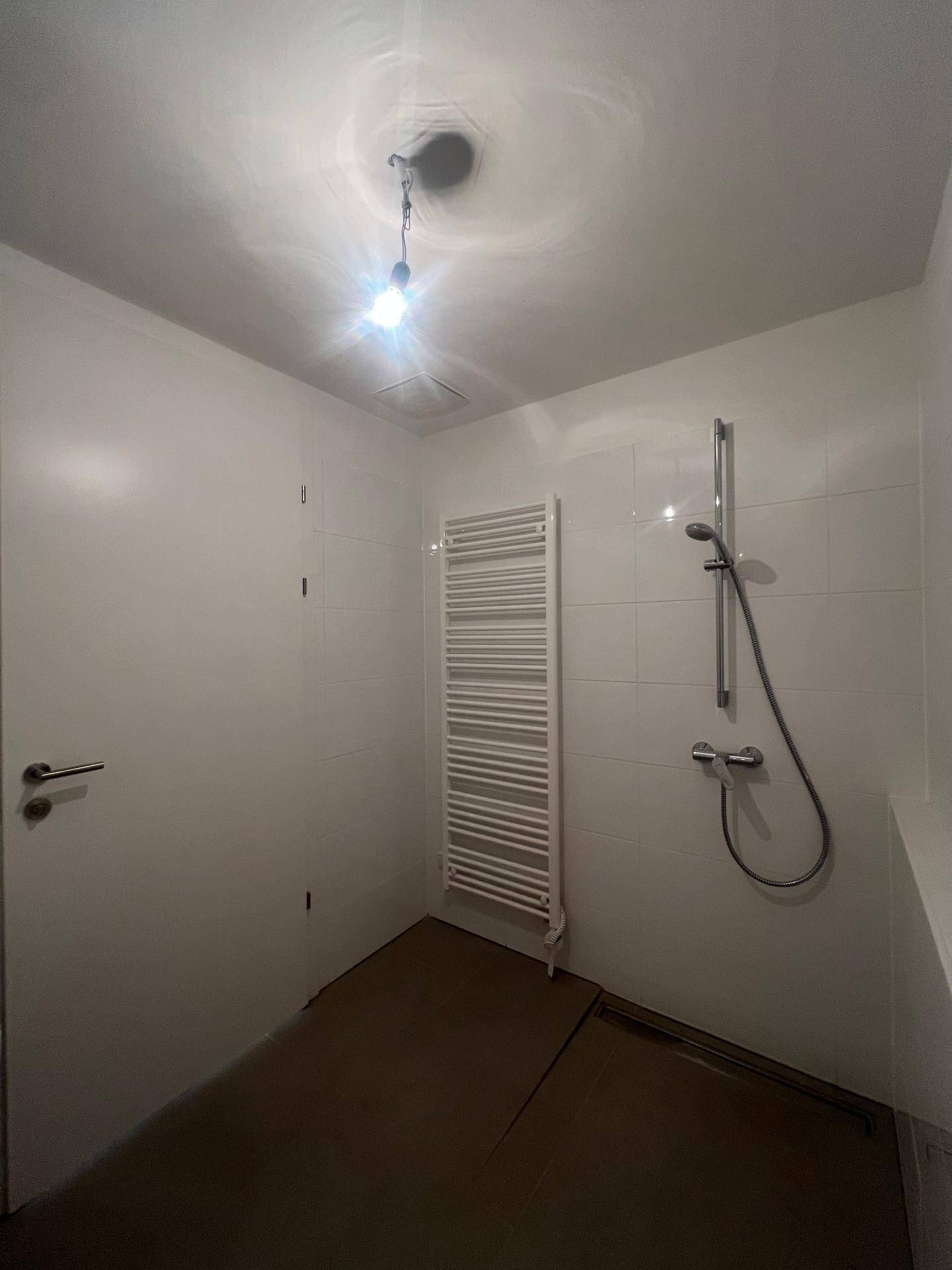 Modernes Badezimmer mit weißen Fliesen, Duschbereich und beheiztem Handtuchhalter.