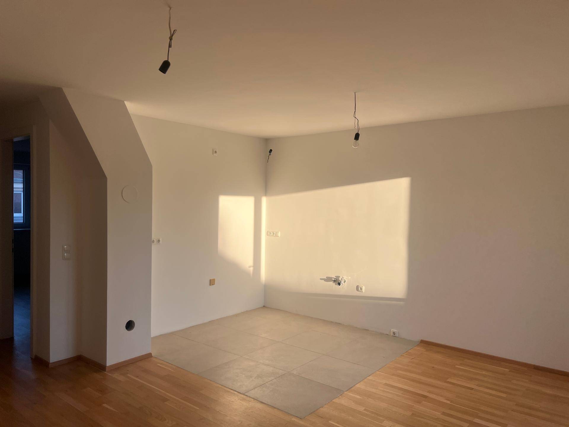 Heller Wohnbereich mit gemischtem Bodenbelag aus Holz und Fliesen, ideal für offene Gestaltung.
