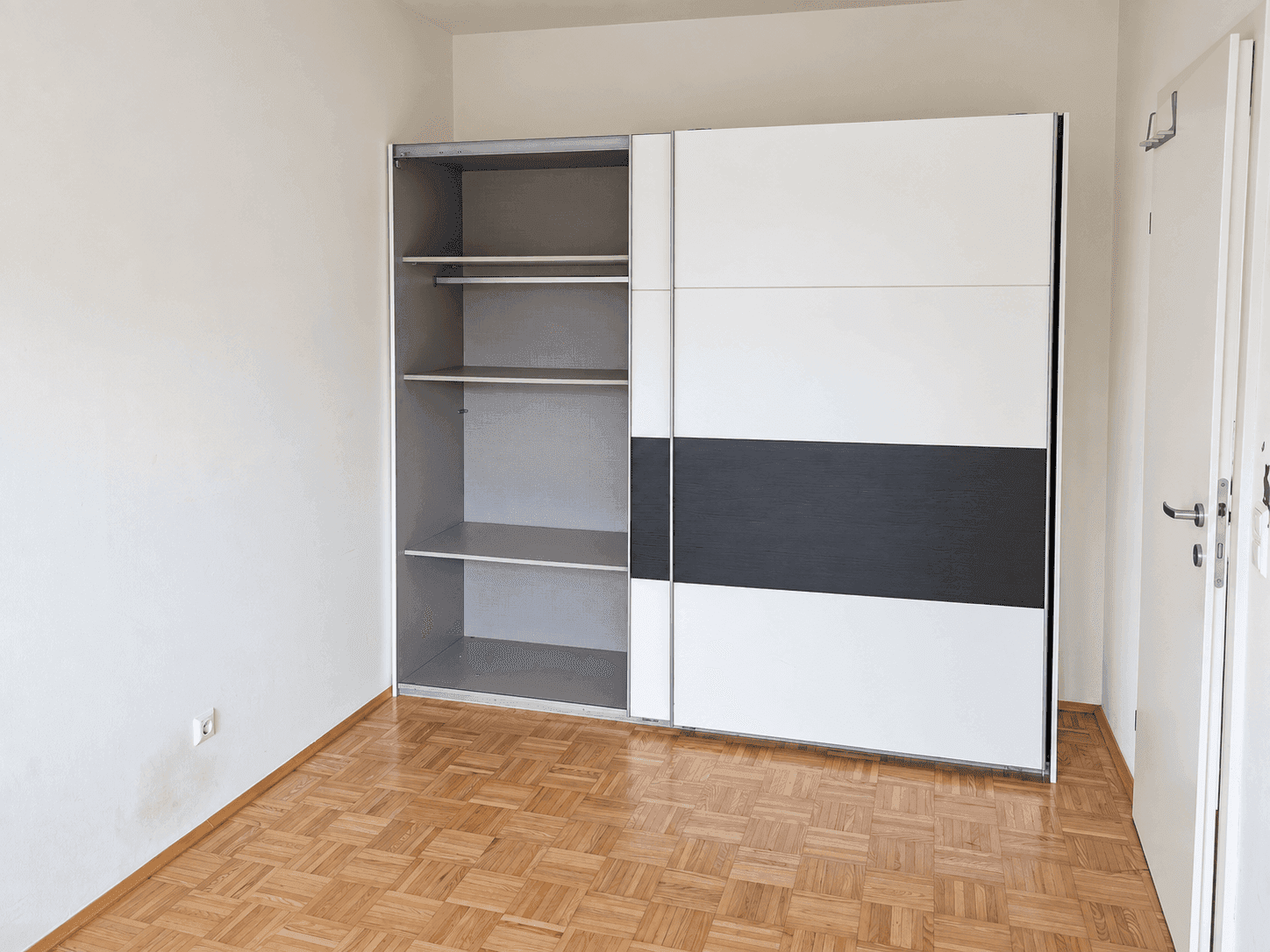 Geräumiges Zimmer mit Parkettboden und großem Schiebetürenschrank, ideal als Schlafzimmer.