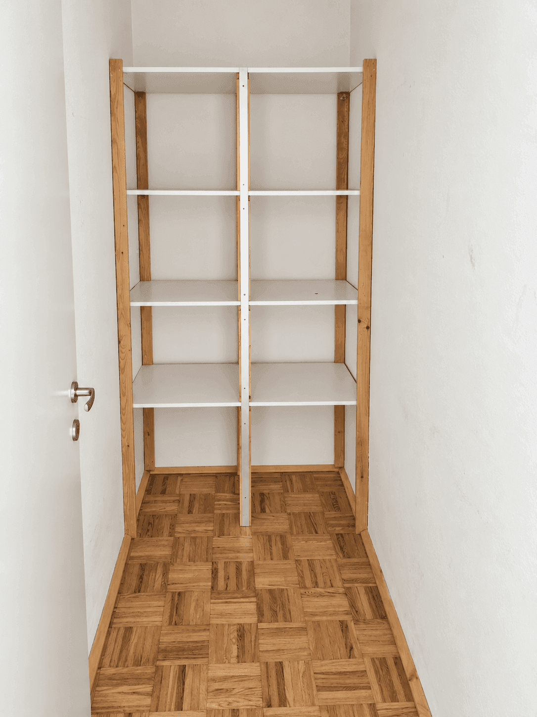 Praktischer Abstellraum mit eingebauten Holzregalen und Parkettboden für zusätzlichen Stauraum.