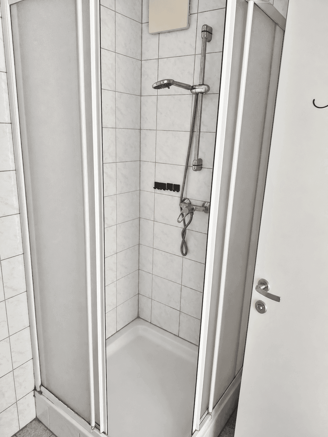Duschbereich im Badezimmer mit weißen Fliesen und einer praktischen Duschkabine.