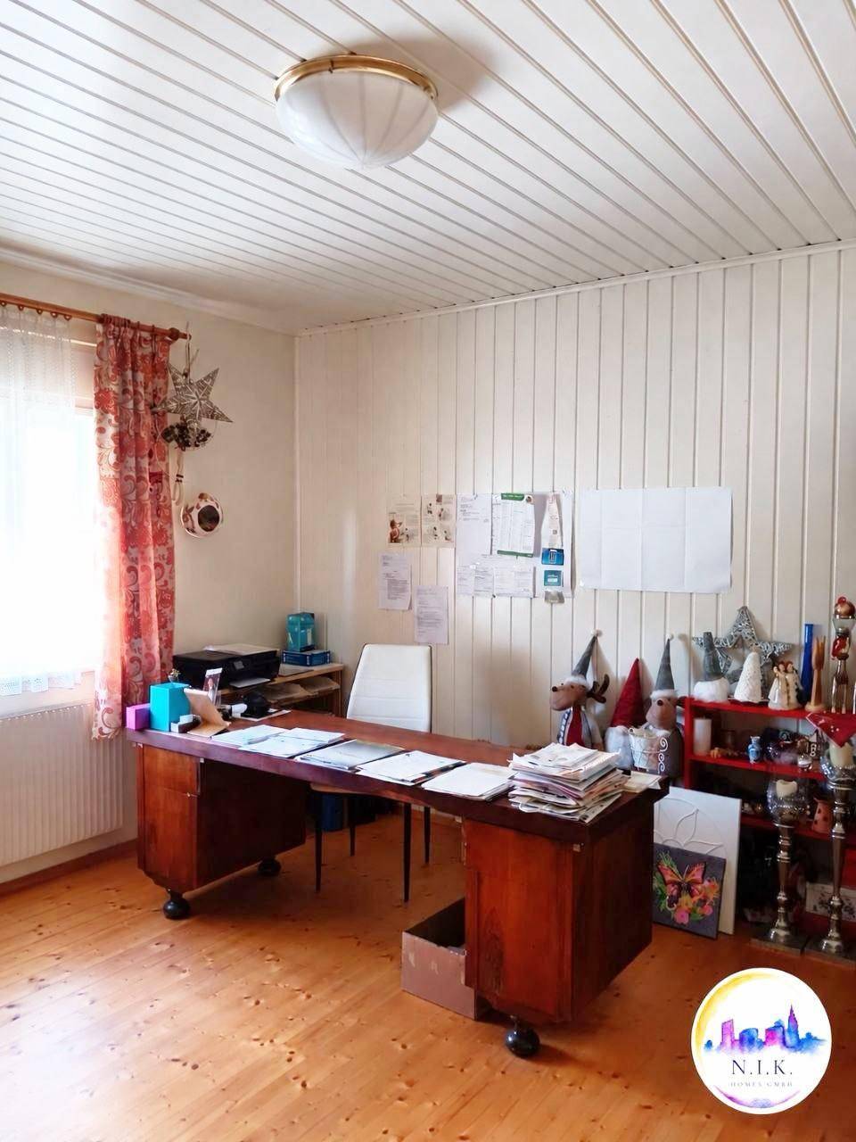 Helles Arbeitszimmer mit Holzvertäfelung an Wänden und Decke sowie einem großen Schreibtisch.