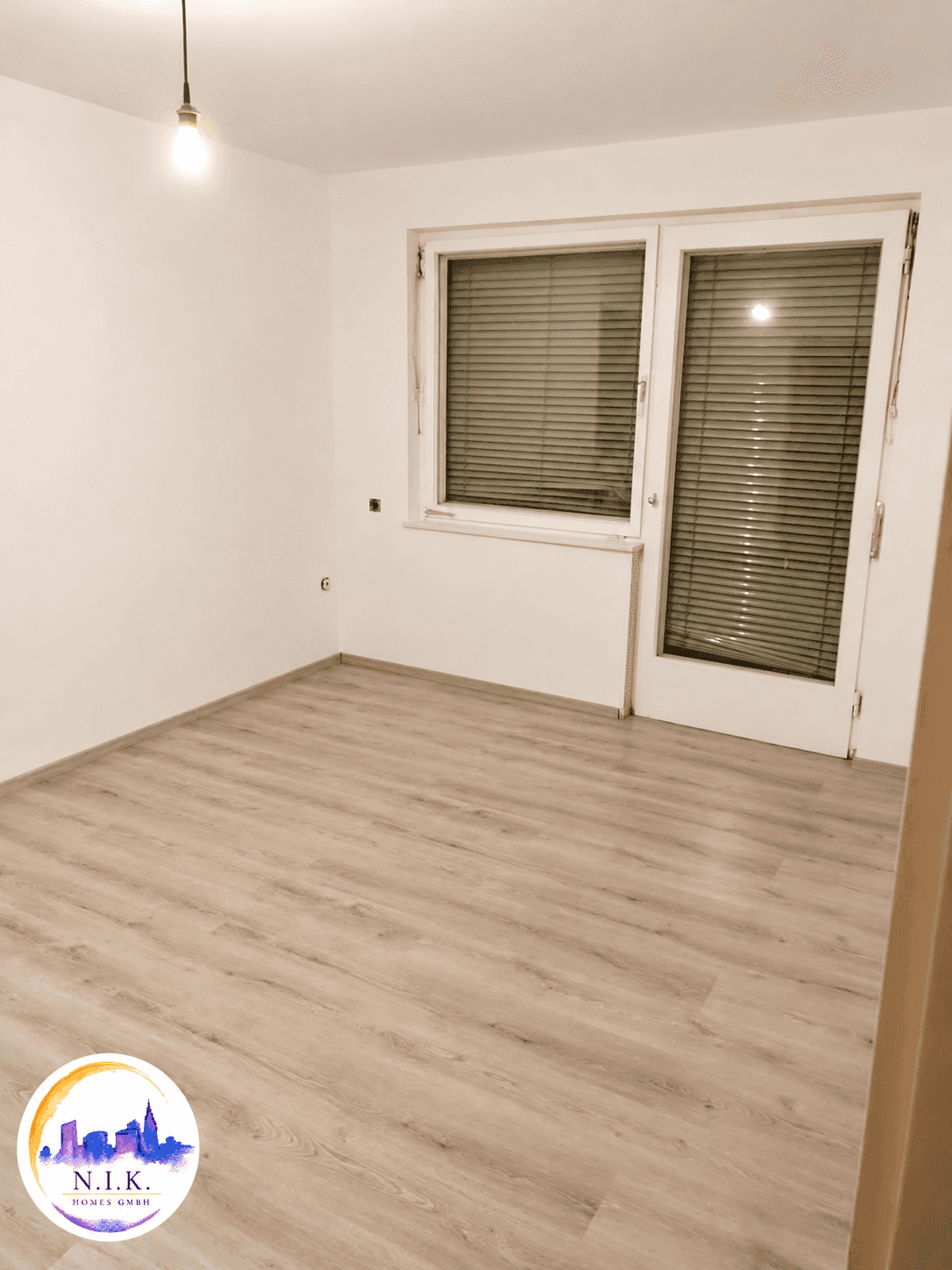 Helles Zimmer mit Laminatboden und Zugang zu einem französischen Balkon oder Fenster.