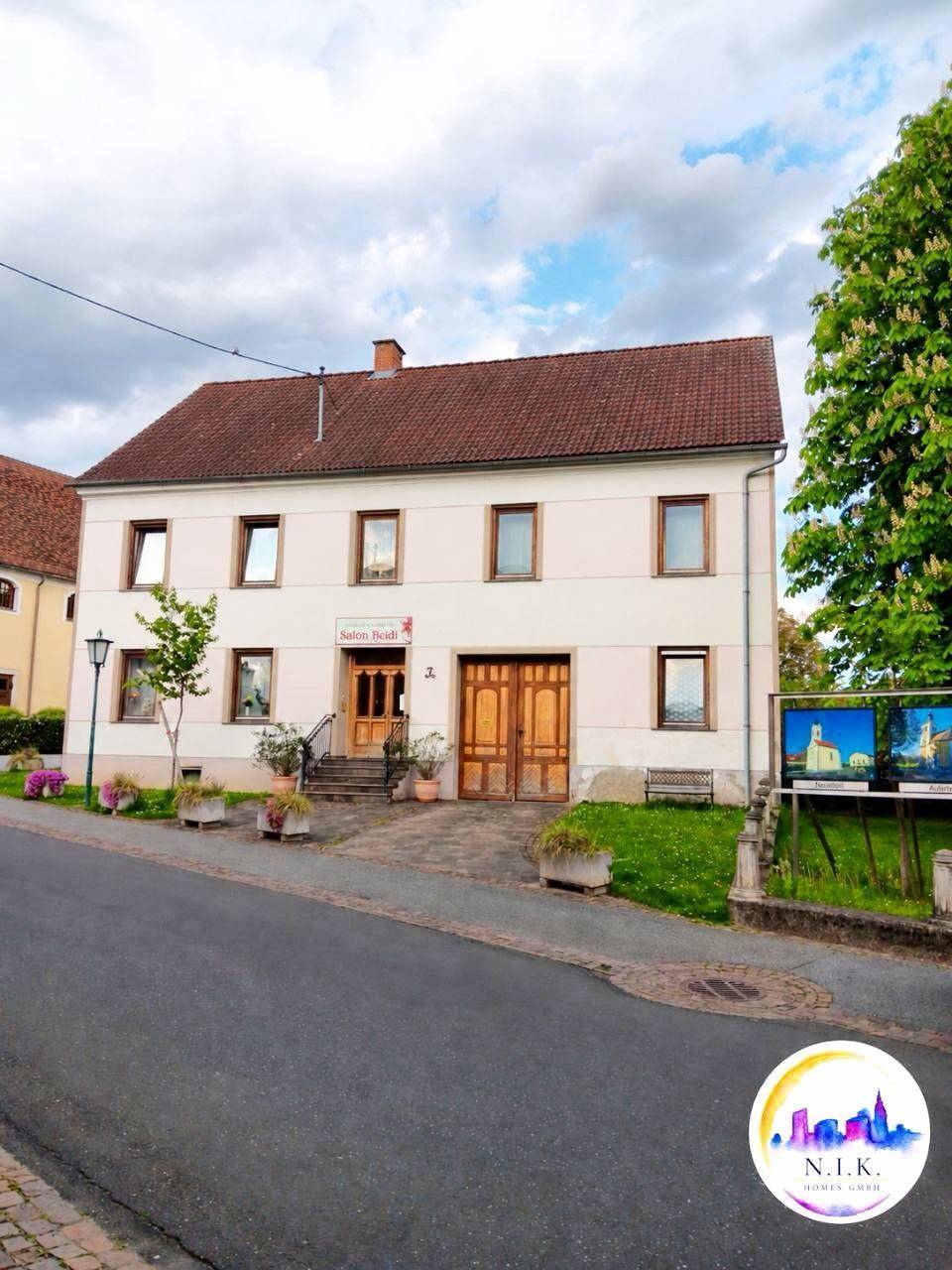 Vorderansicht eines traditionellen Gebäudes mit Holztüren, Fenstern und einem gepflegten Vorgarten.