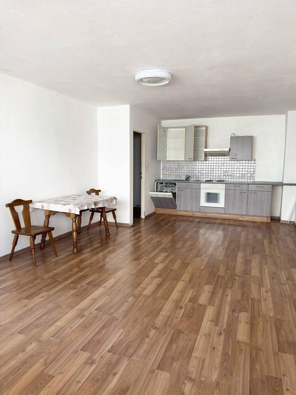 Funktionale Küche mit grauen Schränken, Essbereich und Laminatboden in warmem Holzton.