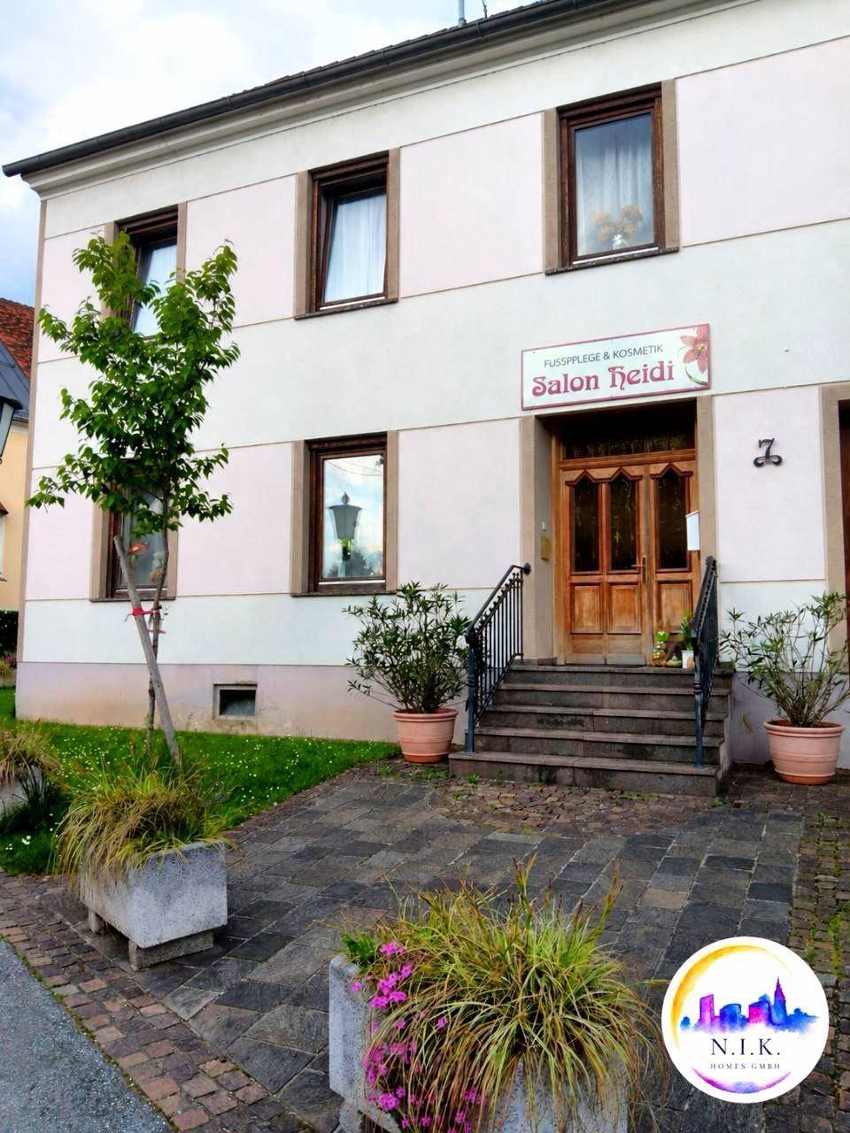 Nahaufnahme des Eingangsbereichs eines Gebäudes mit Holztür, Treppe und einem Geschäftsschild.