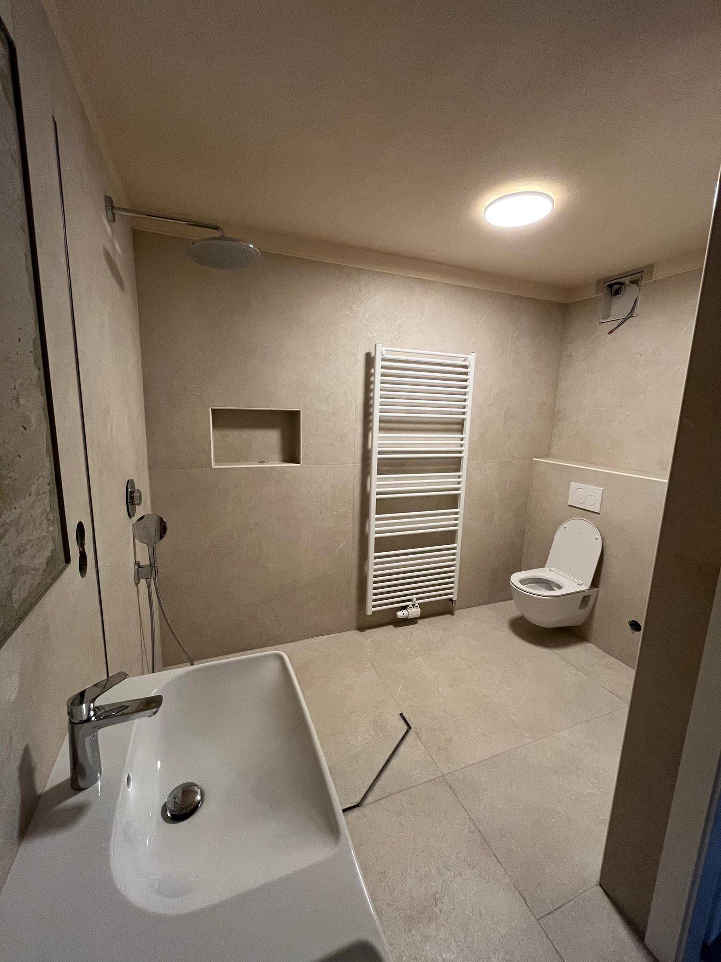 Modernes Badezimmer mit Doppelwaschbecken, Dusche, Toilette und beheiztem Handtuchhalter.