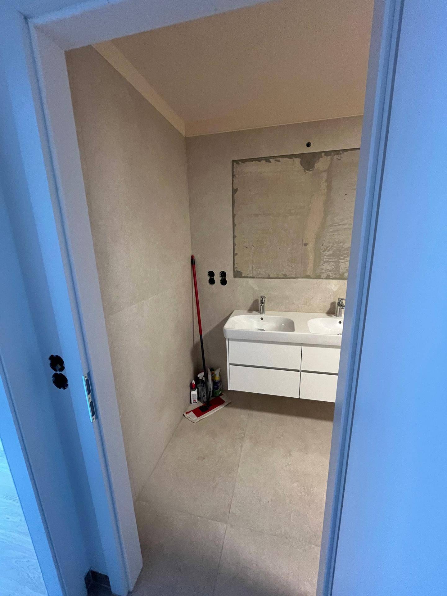 Geräumiges Badezimmer mit Doppelwaschbecken und hellen Fliesen, noch im Bau.