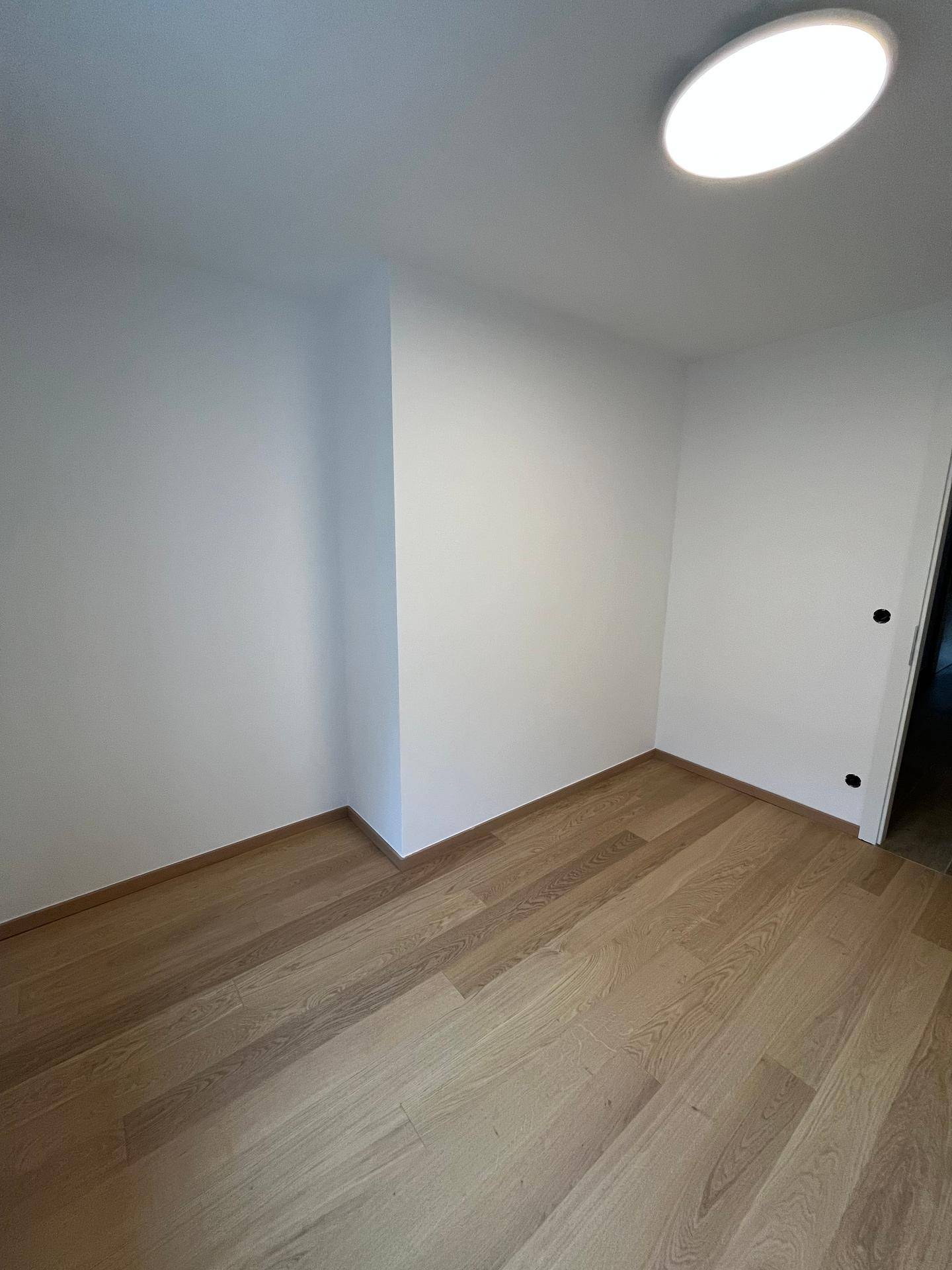 Leeres Zimmer mit Parkettboden und weiß gestrichenen Wänden, bereit für die Einrichtung.