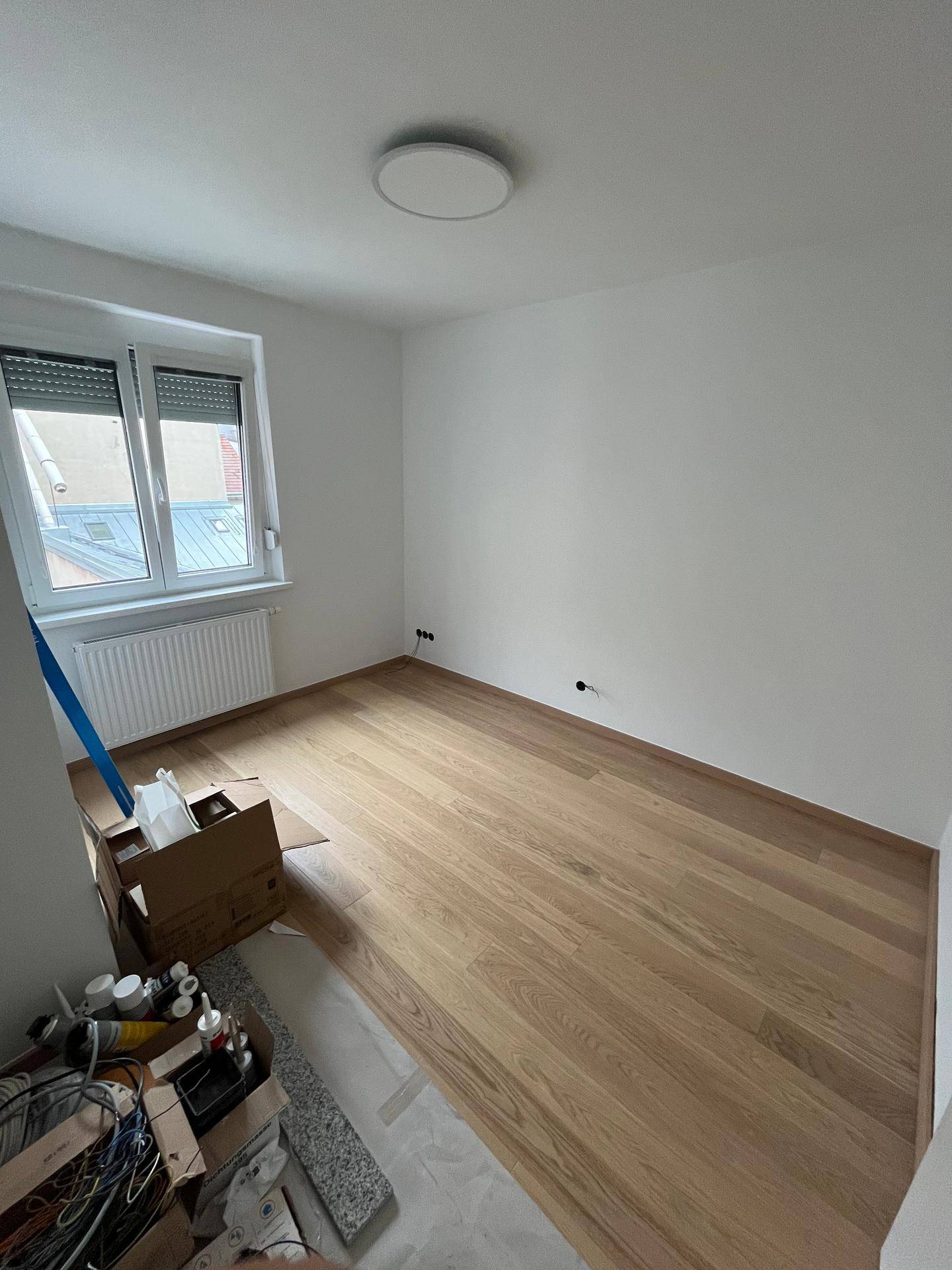 Unmöbliertes Zimmer mit Parkettboden, Fenster und Heizkörper, ideal als Schlaf- oder Arbeitszimmer.