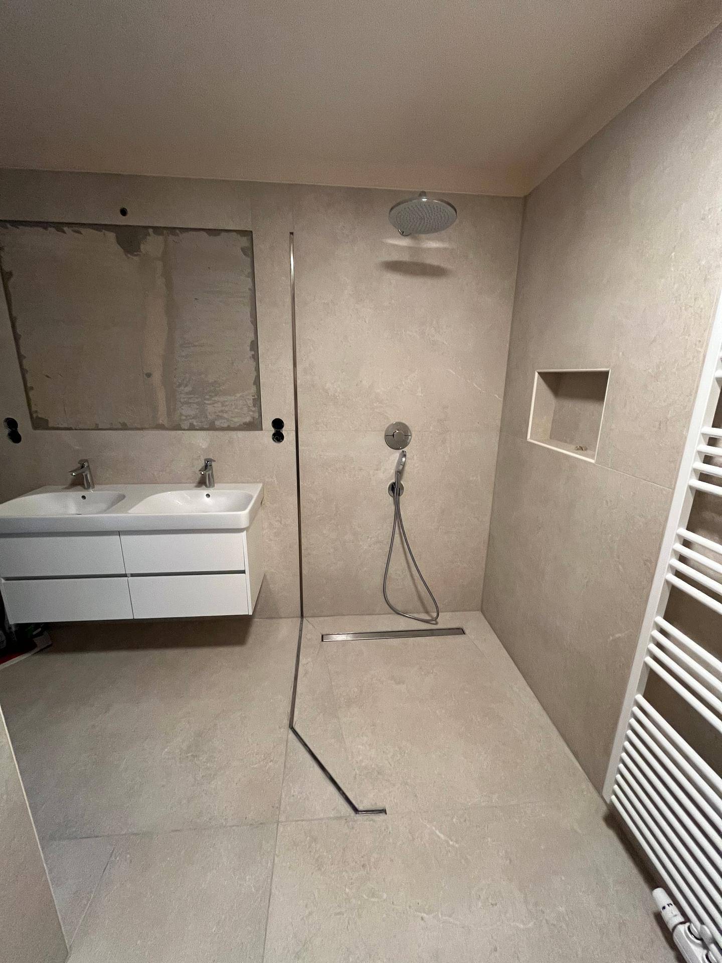 Ebenerdige Dusche mit Regenduschkopf und Doppelwaschbecken in einem modernen Badezimmer.