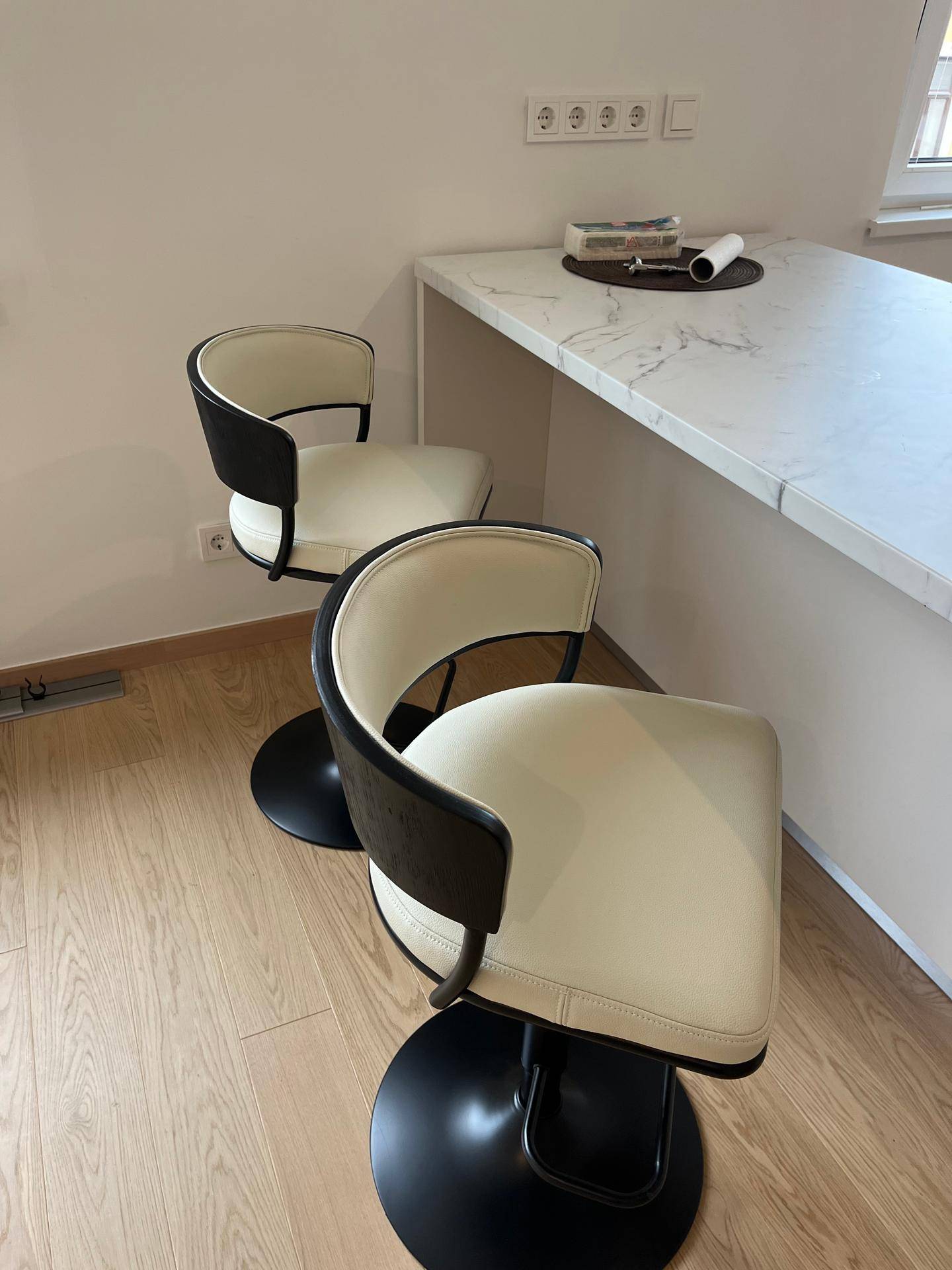 Zwei elegante Barhocker an einer modernen Kücheninsel mit Marmor-Arbeitsplatte.