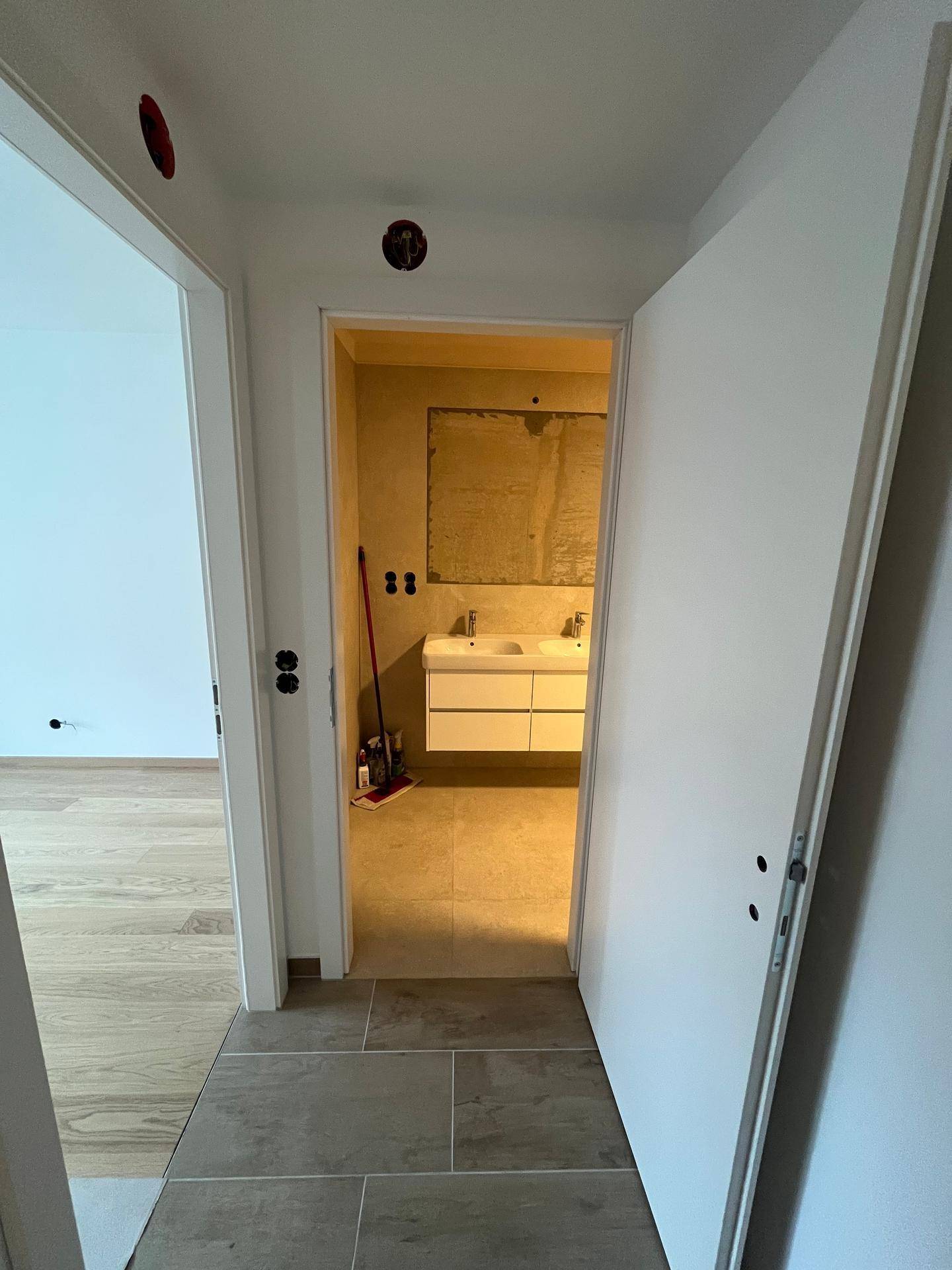 Flur mit Blick auf ein Badezimmer mit Doppelwaschbecken und moderner Ausstattung.