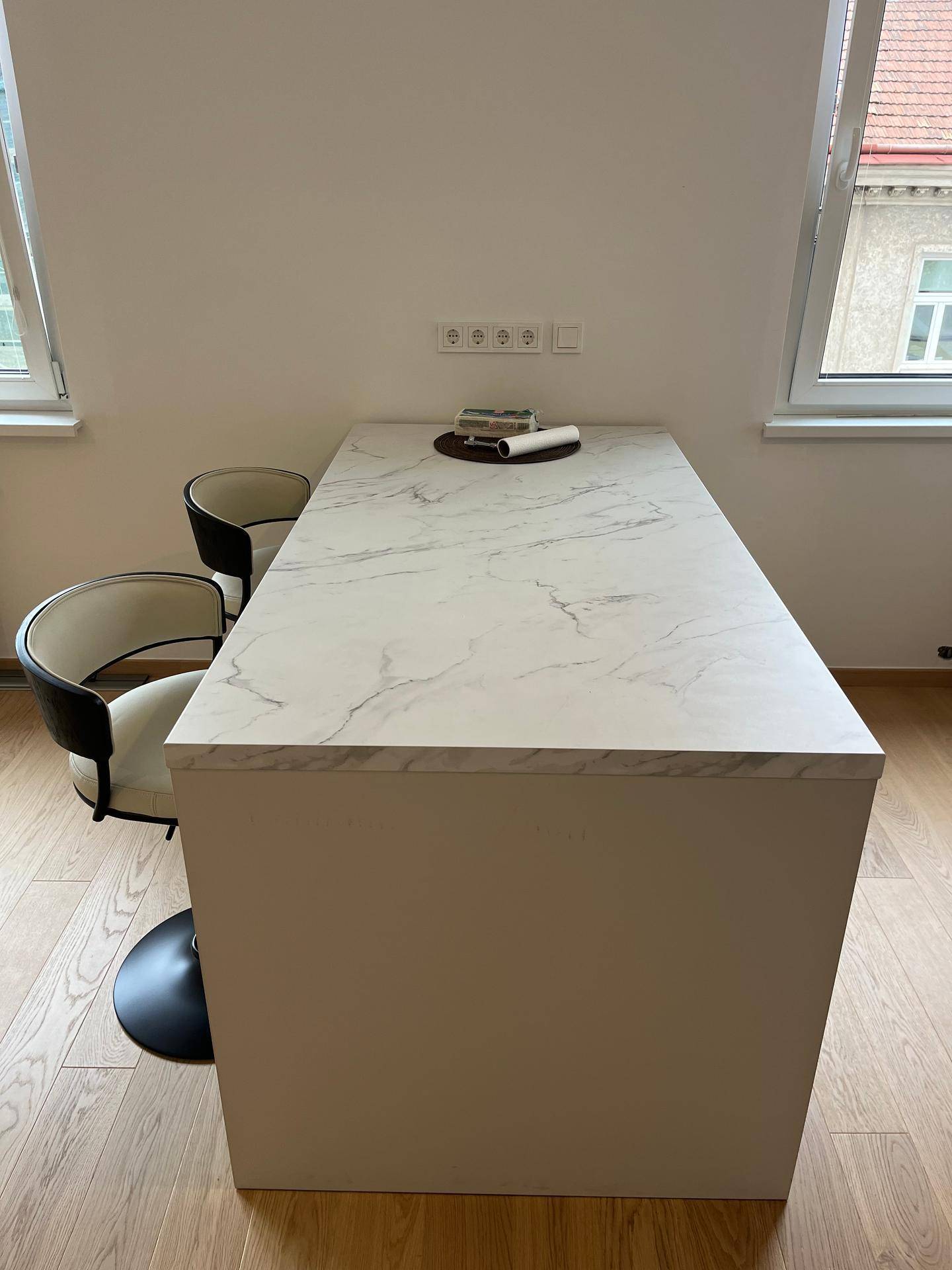 Moderne Kücheninsel mit Marmor-Arbeitsplatte und zwei stilvollen Barhockern, ideal für Frühstück.