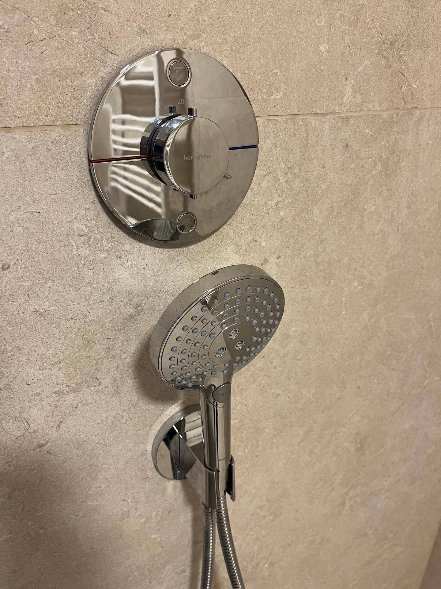 Handbrause und Thermostatmischer von Hansgrohe in einem modernen Duschbereich.