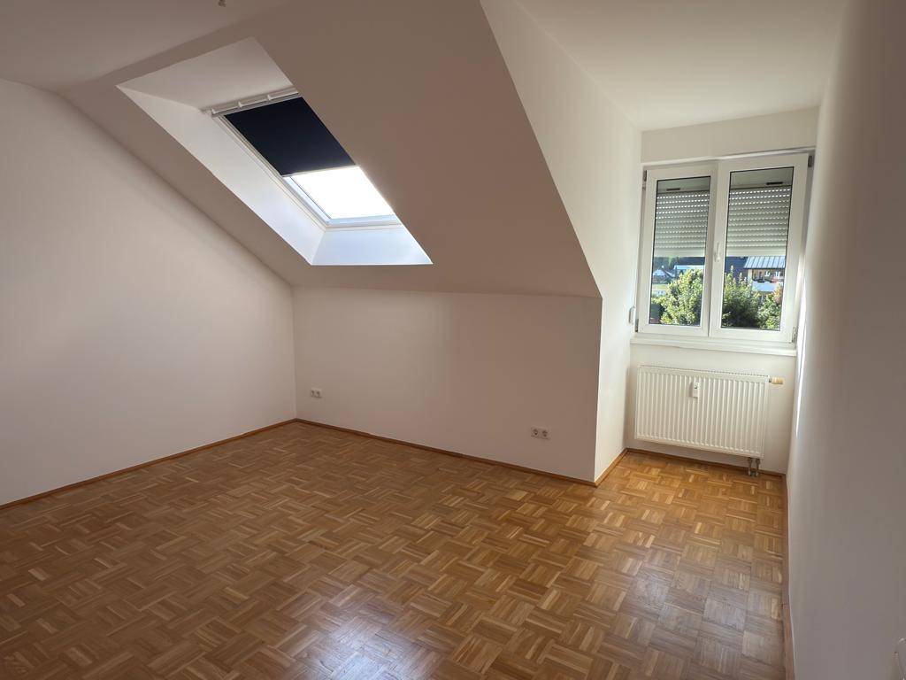 Geräumiges Schlafzimmer im Dachgeschoss mit Parkettboden und viel Tageslicht.