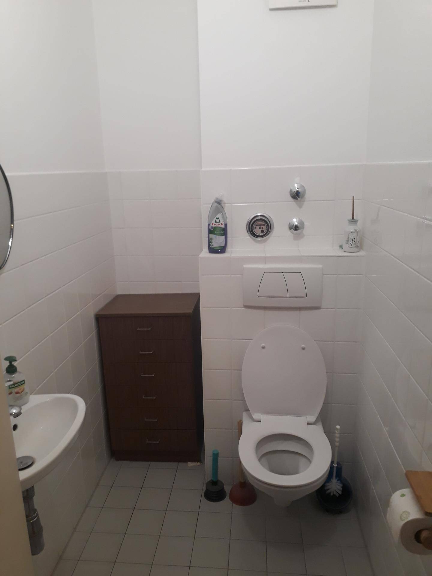 Kleines Gäste-WC mit wandhängendem WC, Waschbecken und weißen Fliesen an den Wänden.