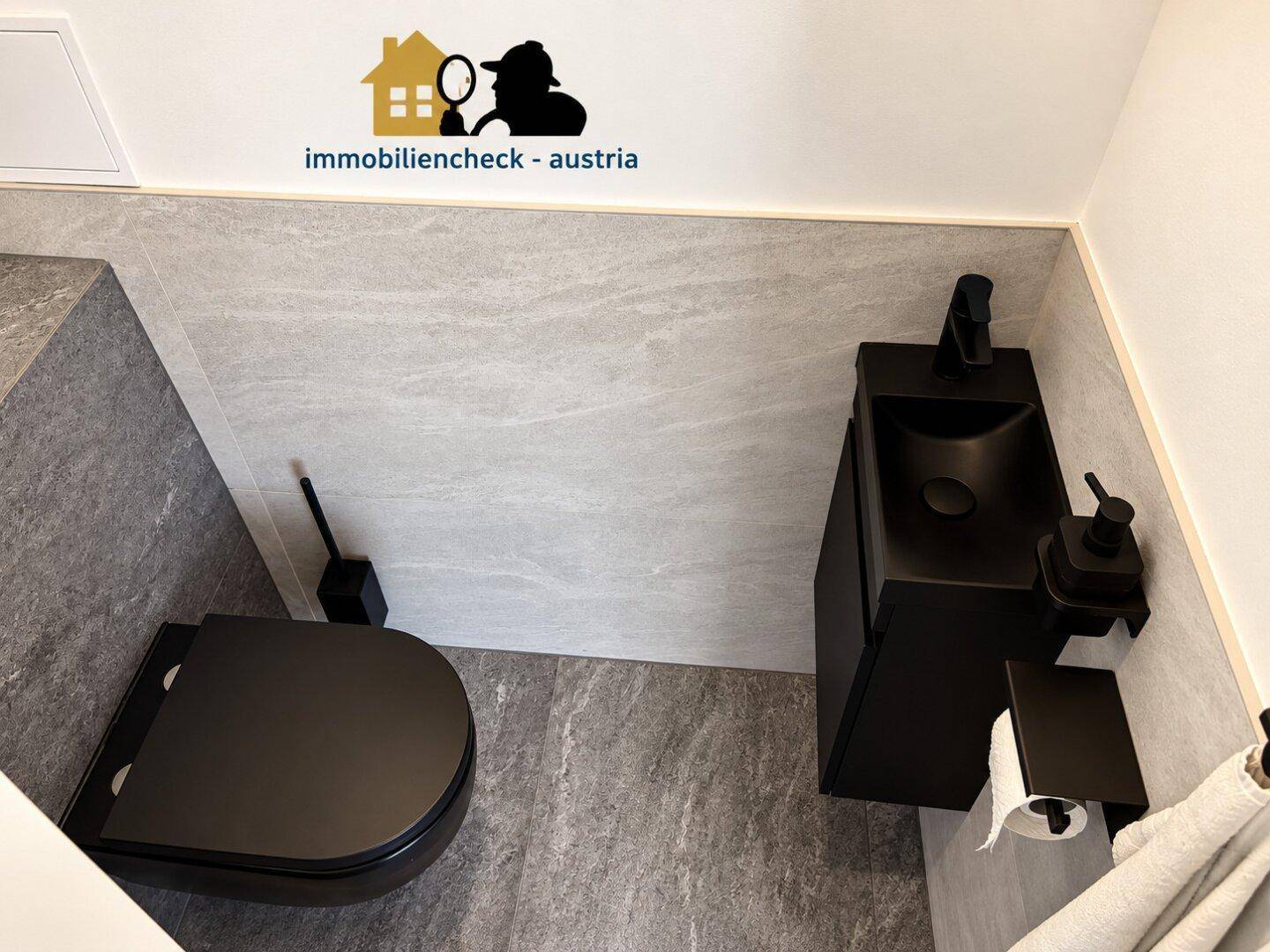 Modernes Gäste-WC mit schwarzen Armaturen, Wand-WC und grauen Fliesen.