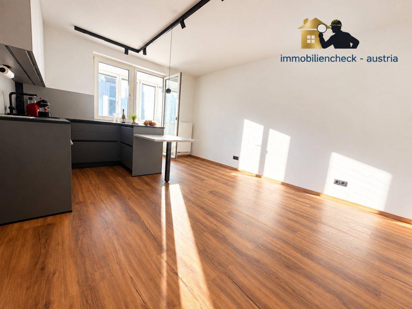 Helle moderne Küche mit grauen Schränken, dunkler Arbeitsplatte und Zugang zu einem Balkon.