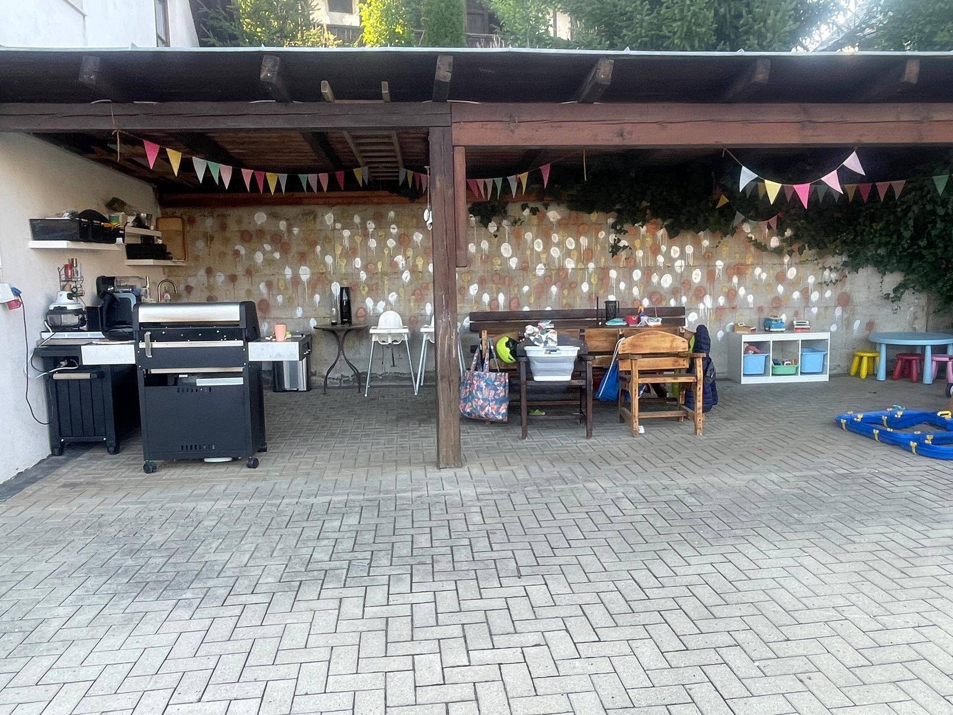 Überdachter Außenbereich mit Grillstation, Sitzgelegenheiten und festlicher Dekoration.