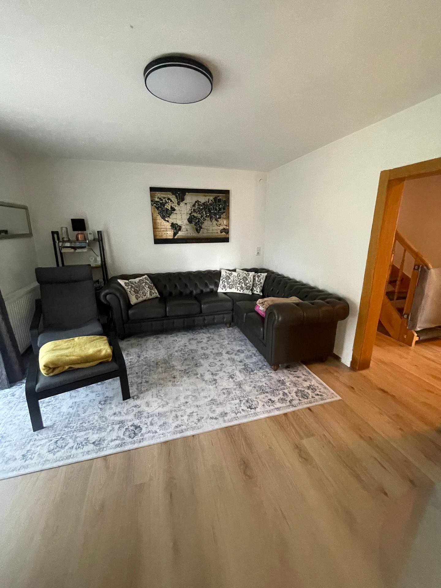 Geräumiges Wohnzimmer mit großem Ecksofa, Teppich und Holzboden.