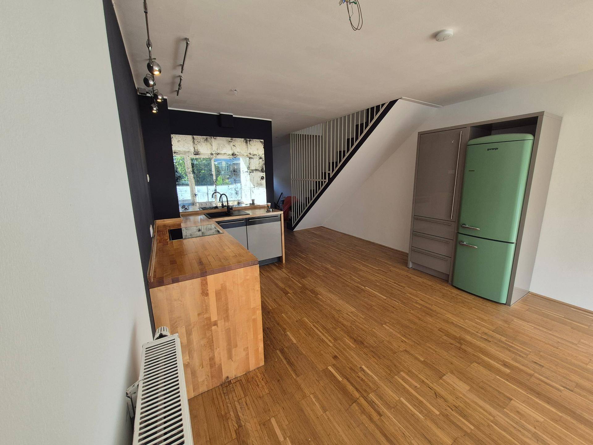 Moderne Küche mit Holzarbeitsplatte, grauen Unterschränken und auffälligem grünem Kühlschrank.