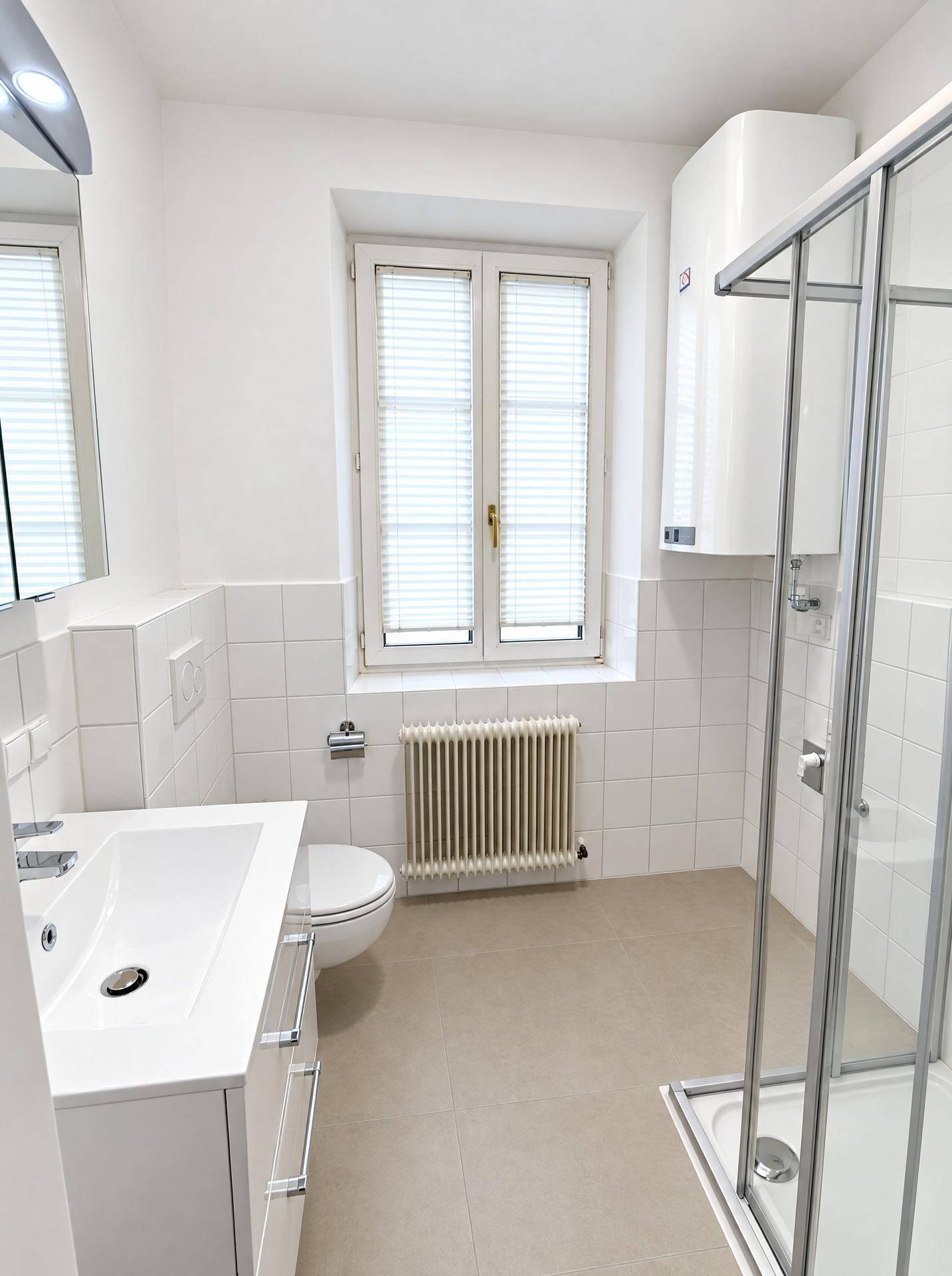Modernes Badezimmer mit Duschkabine, WC, Waschbecken und Spiegelschrank, hell gefliest.