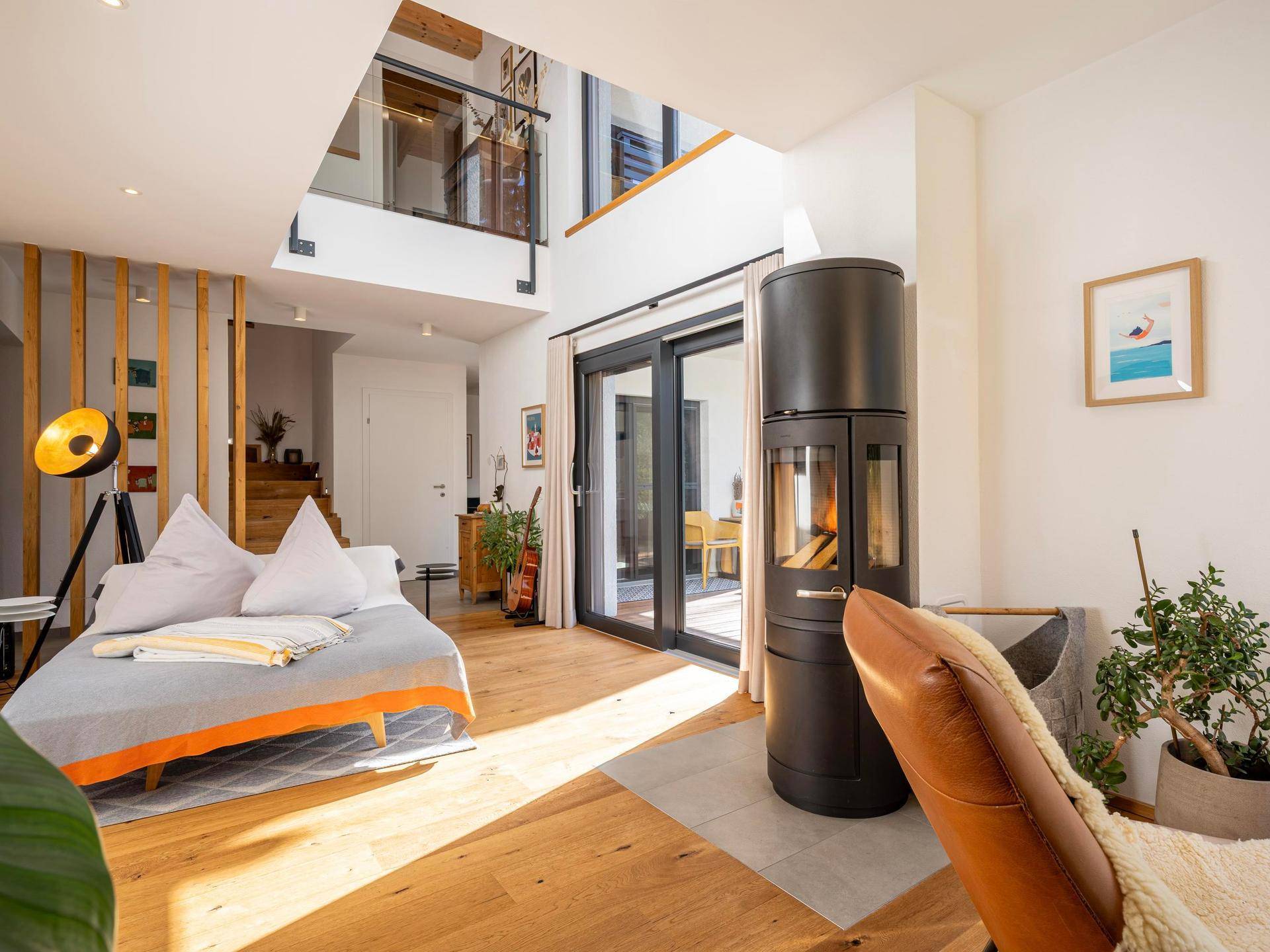 Helles Wohnzimmer mit modernem Holzofen, Holzboden und offener Galerie.
