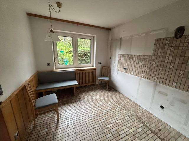 Geräumige Küche mit Fliesenboden, vorbereitet für Einbaumöbel und mit Fensterblick.