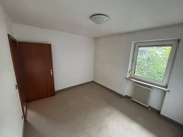 Helles Schlafzimmer mit Teppichboden, Fenster und Heizkörper.