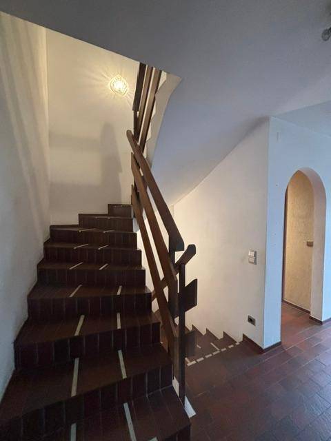 Holztreppe mit Geländer führt in die oberen Stockwerke des Hauses.