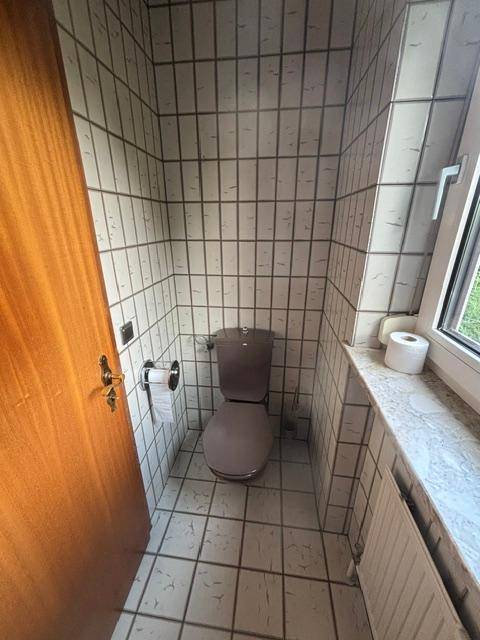 Kleines Gäste-WC mit Fliesenboden, Fenster und einfacher Ausstattung.