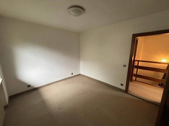 Schlafzimmer mit Teppichboden und Zugang zum Flur.