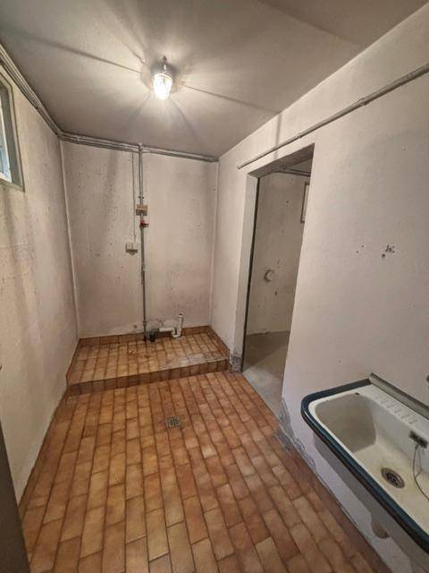 Kellerraum mit Waschbecken und Fliesenboden, ideal als Waschküche nutzbar.