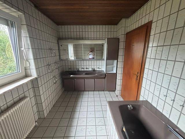 Badezimmer mit Doppelwaschbecken, Spiegelschrank und Fliesenboden.
