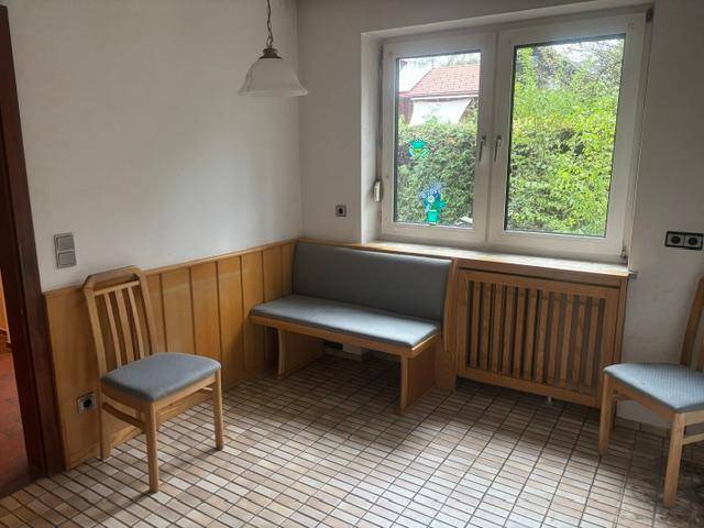 Gemütliche Küche mit eingebauter Sitzbank, Holzvertäfelung und Blick in den Garten.