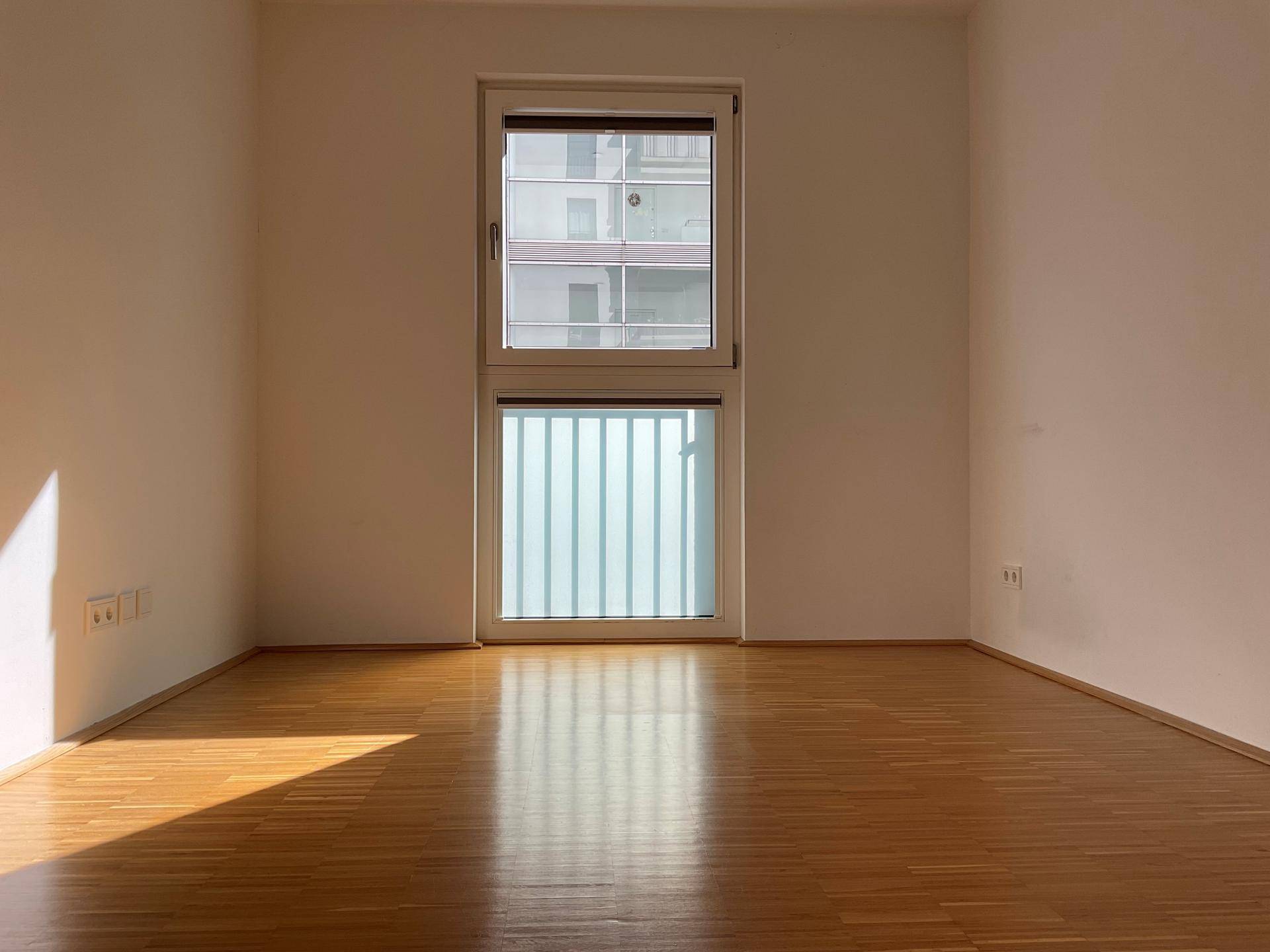 Heller Raum mit großem Fenster und Holzparkett, ideal für Schlafzimmer oder Büro, unmöbliert.