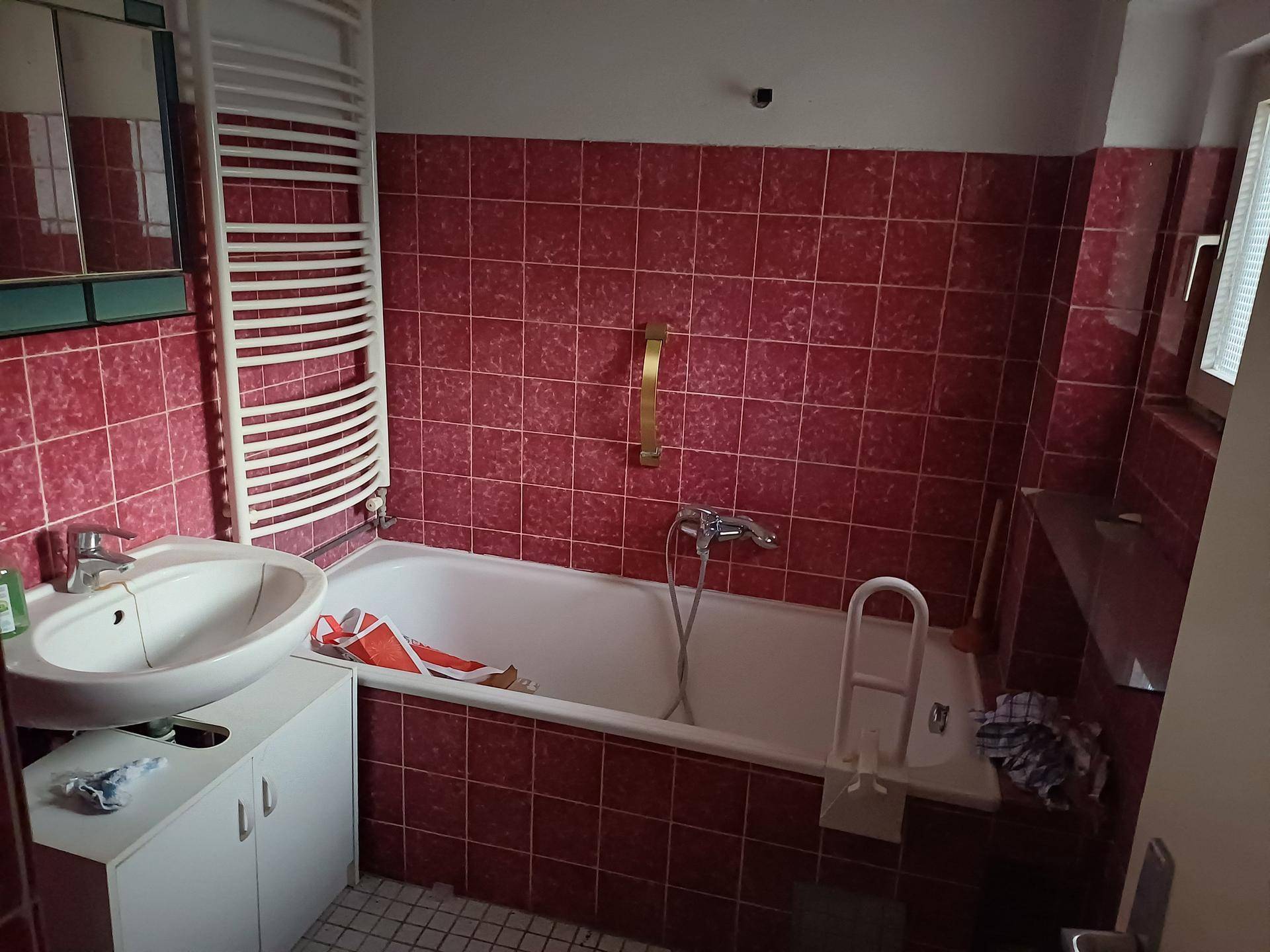 Badezimmer mit roten Wandfliesen, einer Badewanne und einem beheizten Handtuchhalter.