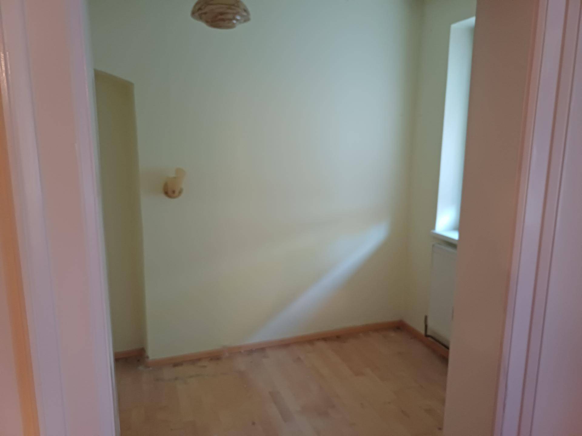 Kleiner, leerer Raum mit Holzdielenboden und einem Fenster, bereit zur Renovierung.