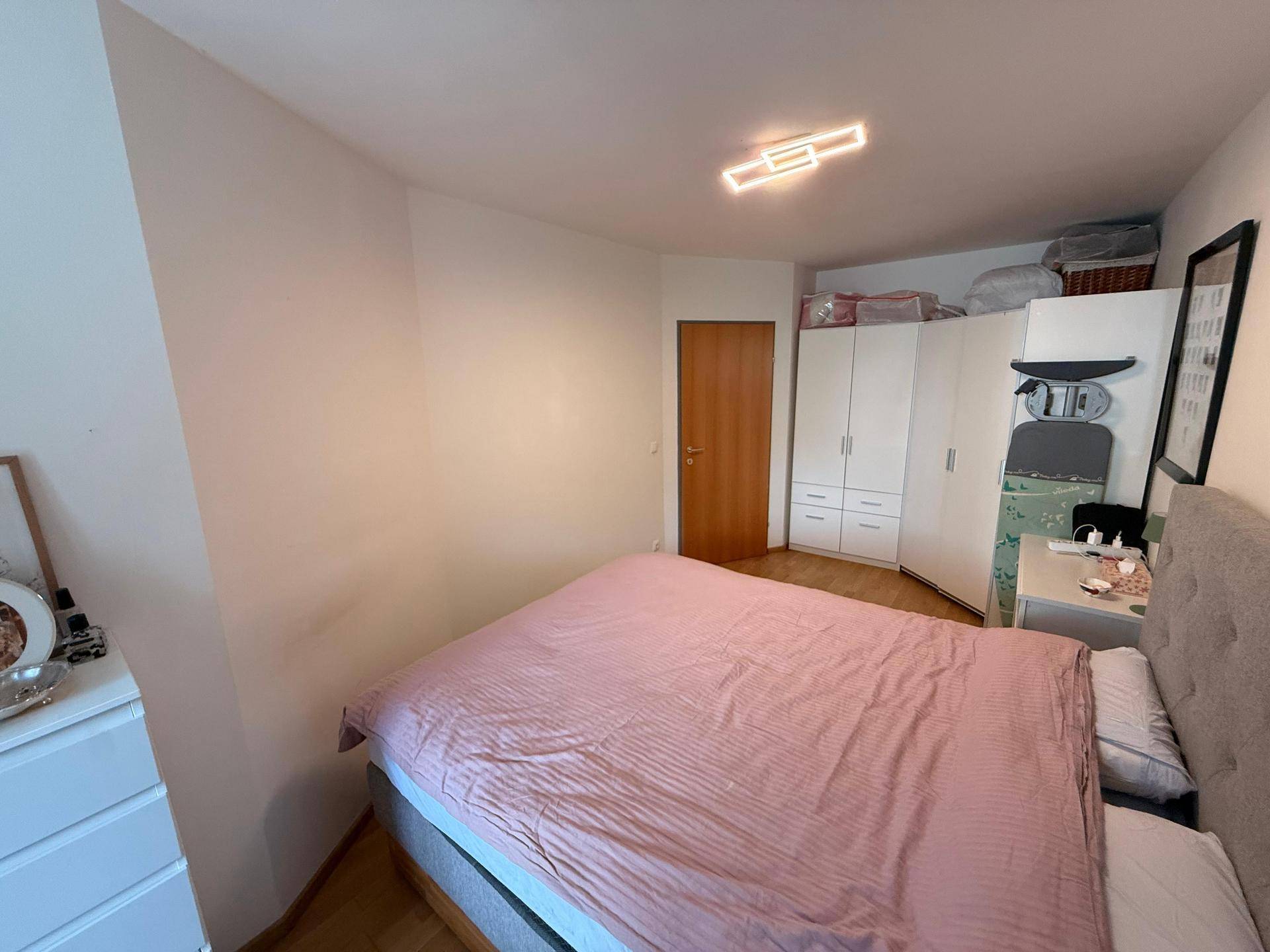 Schlafzimmer mit Doppelbett, weißen Kleiderschränken und Holzboden, bietet viel Stauraum.